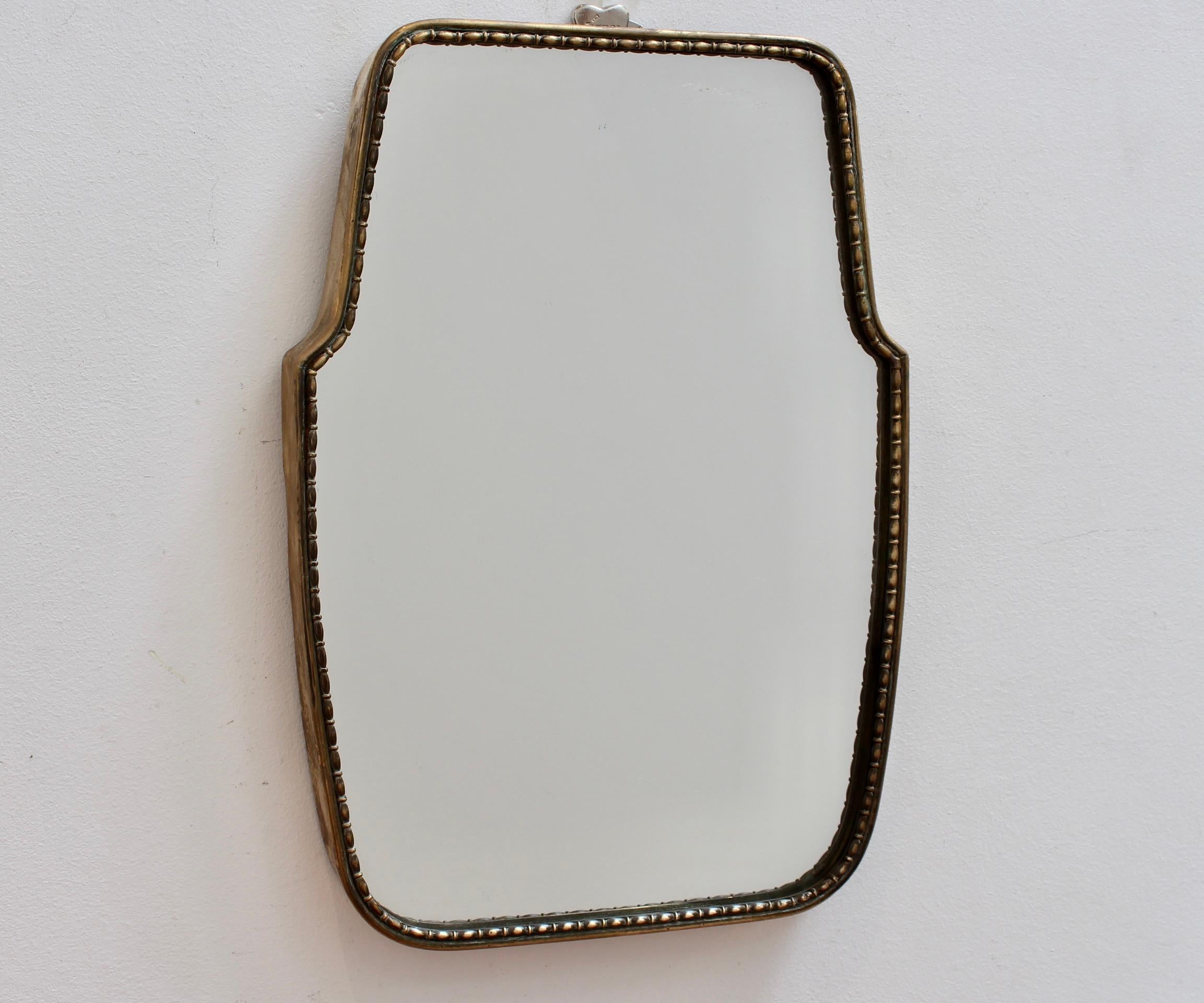 Mid-Century Italian wall mirror with brass frame and beading (circa 1950s). This mirror is simply elegant and characterful in a modern, Gio Ponti style. It is a relatively small size, classically shaped, with a delightful beading adding visual
