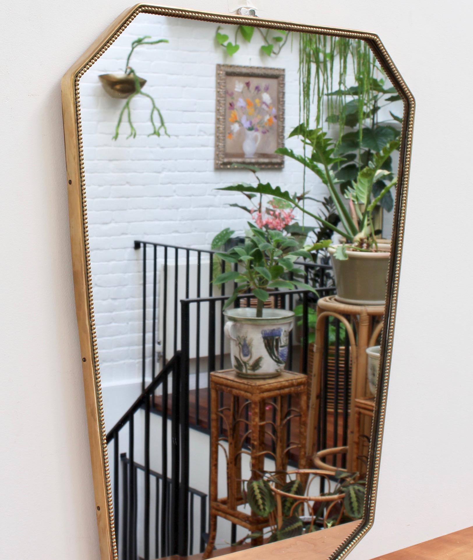 Midcentury Italian wall mirror with brass frame (circa 1950s). This mirror is simply elegant and characterful in a modern, Gio Ponti style. It is classically-shaped with confident angles and delightful beading around the brass frame. The mirror is