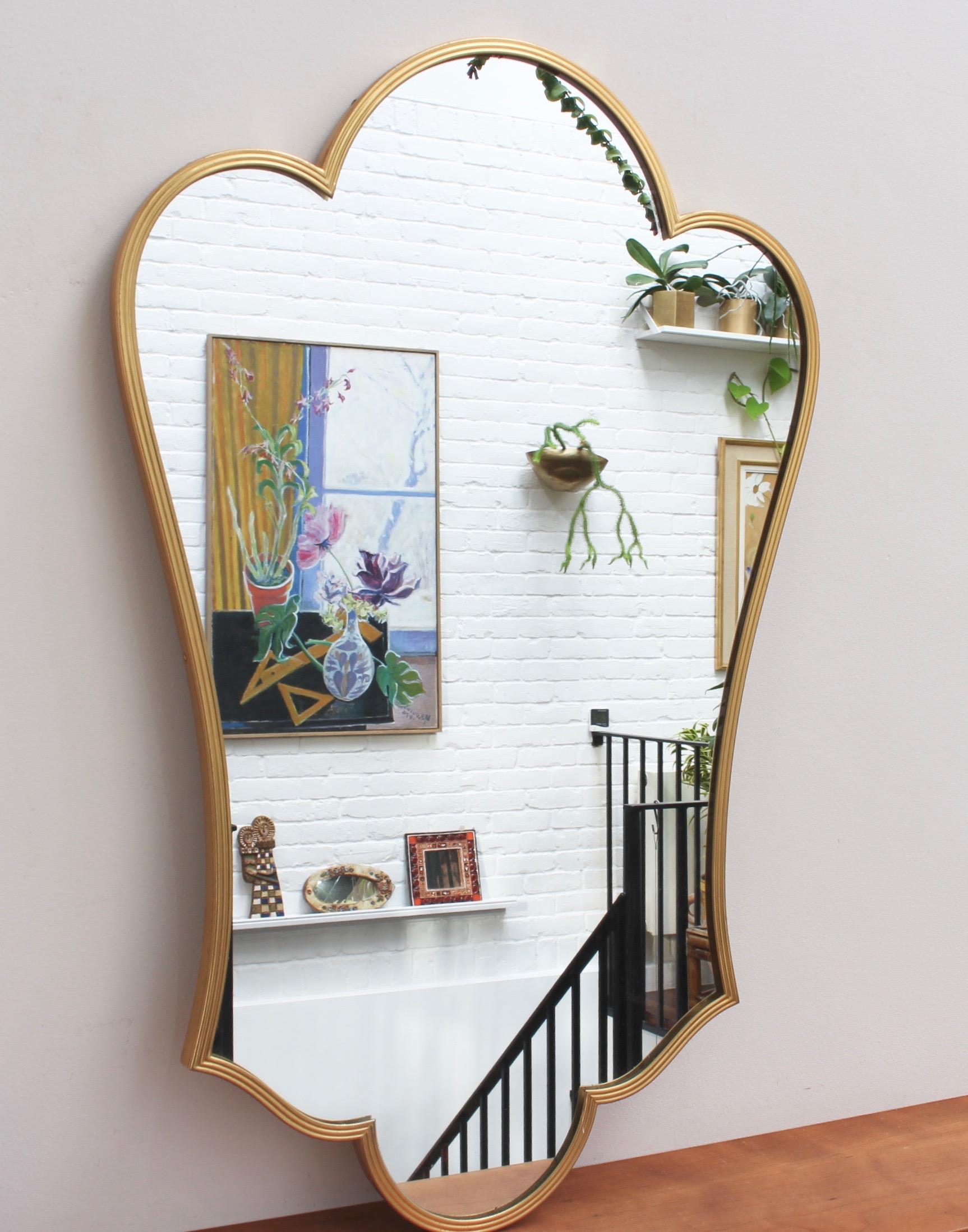 Midcentury Italian wall mirror with brass frame (circa 1950s). This mirror is simply elegant and characterful in a modern, Gio Ponti style. It is large, beautifully fleur-de-lis shaped with sensuous curves - timeless and elegant. Overall it is in