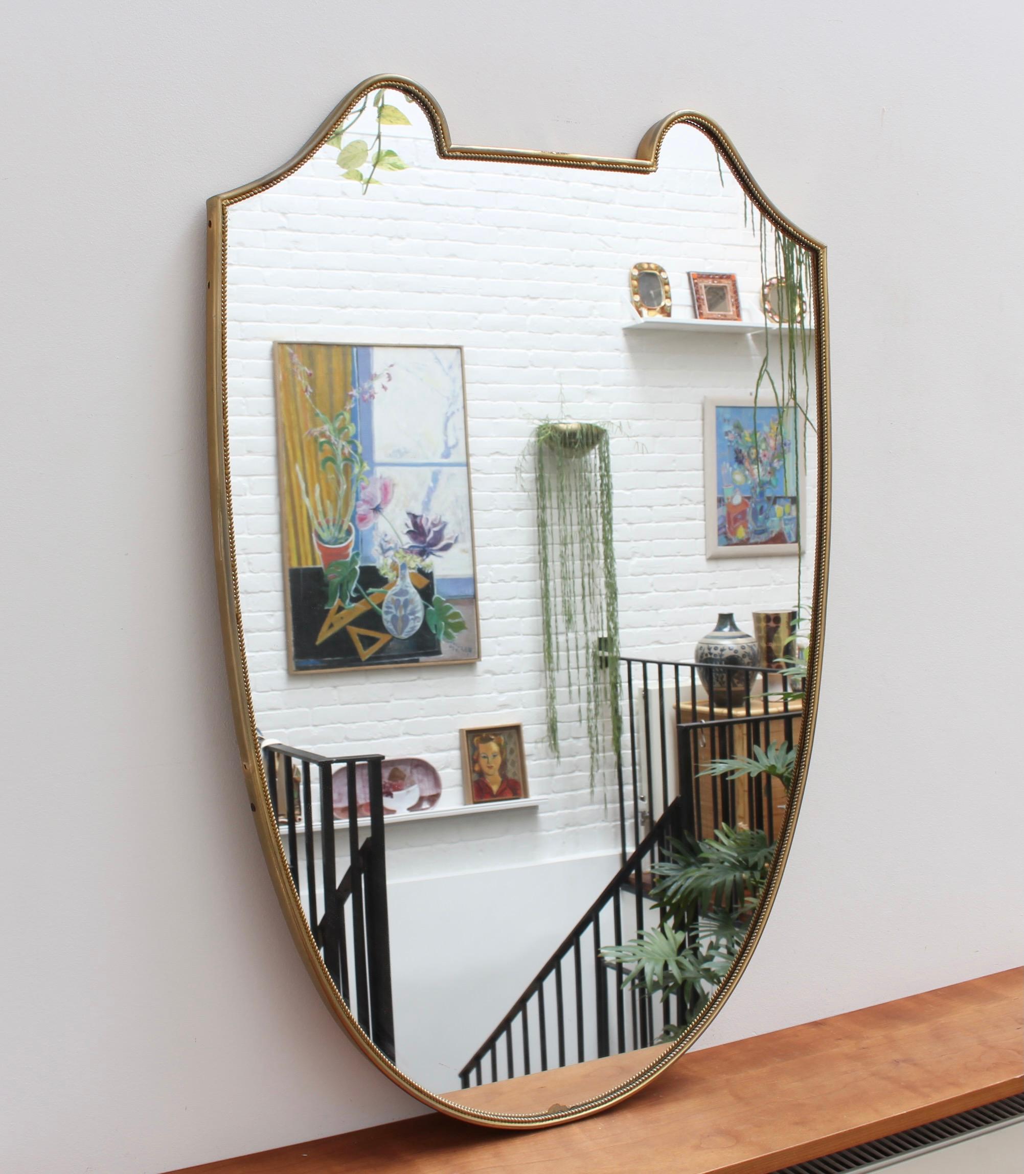 Mid-Century Italian wall mirror with brass frame, circa 1950s. This mirror is substantial, solid and at once elegant. It is the Sophia Lauren of vintage mirrors with its incredible looks, charming personality and characterful beauty mark that others