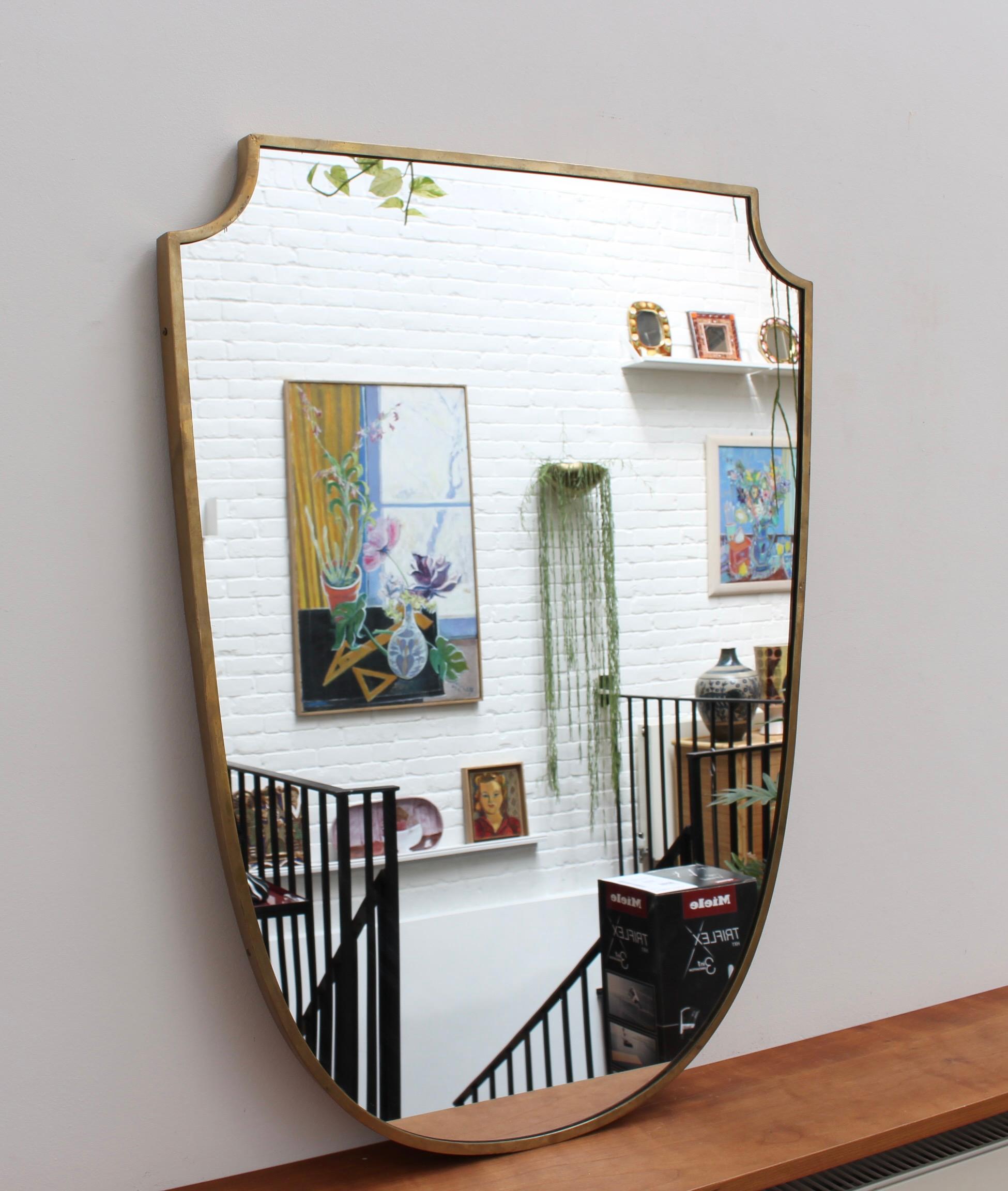 Mid-Century Italian wall mirror with brass frame, circa 1950s. This mirror is simply elegant and characterful in a modern Gio Ponti style. It is crest-shaped and in overall good condition. There are some minor blemishes on the frame over the
