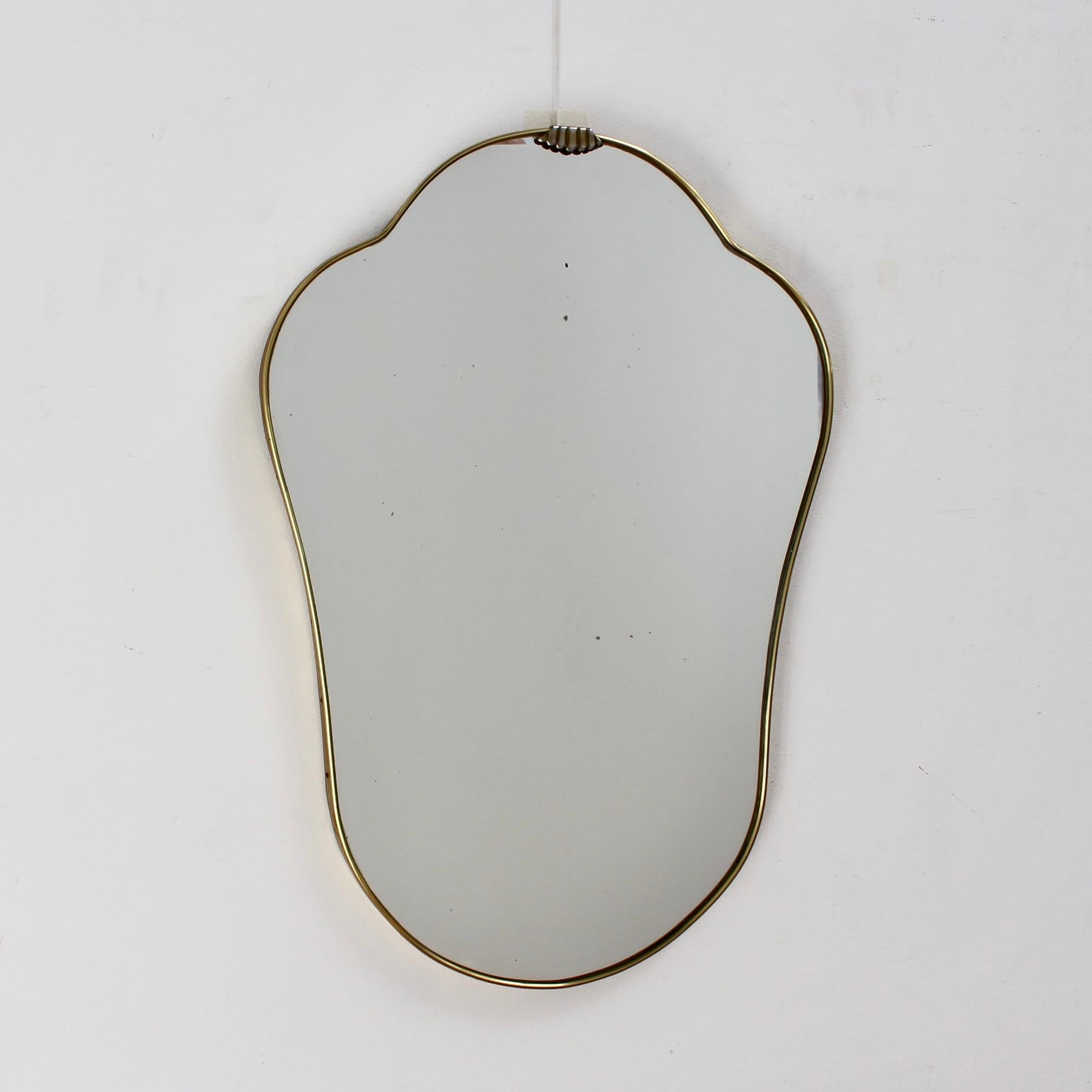 Mid-century Italian wall mirror with brass frame (circa 1950s). The mirror sports a very original shape - always classically elegant and distinctive in a modern Gio Ponti style. In fair overall condition, a characterful vintage patina is on the