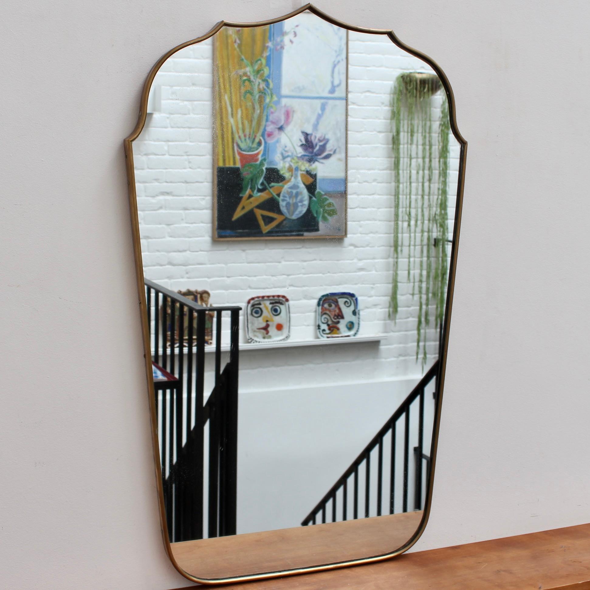 Mid-Century Italian wall mirror with brass frame (circa 1950s). This mirror incorporates a somewhat Arabesque form at the top with elegant curves and distinct points. It has charm, shape and a unique vintage personality. The glass as shown in the