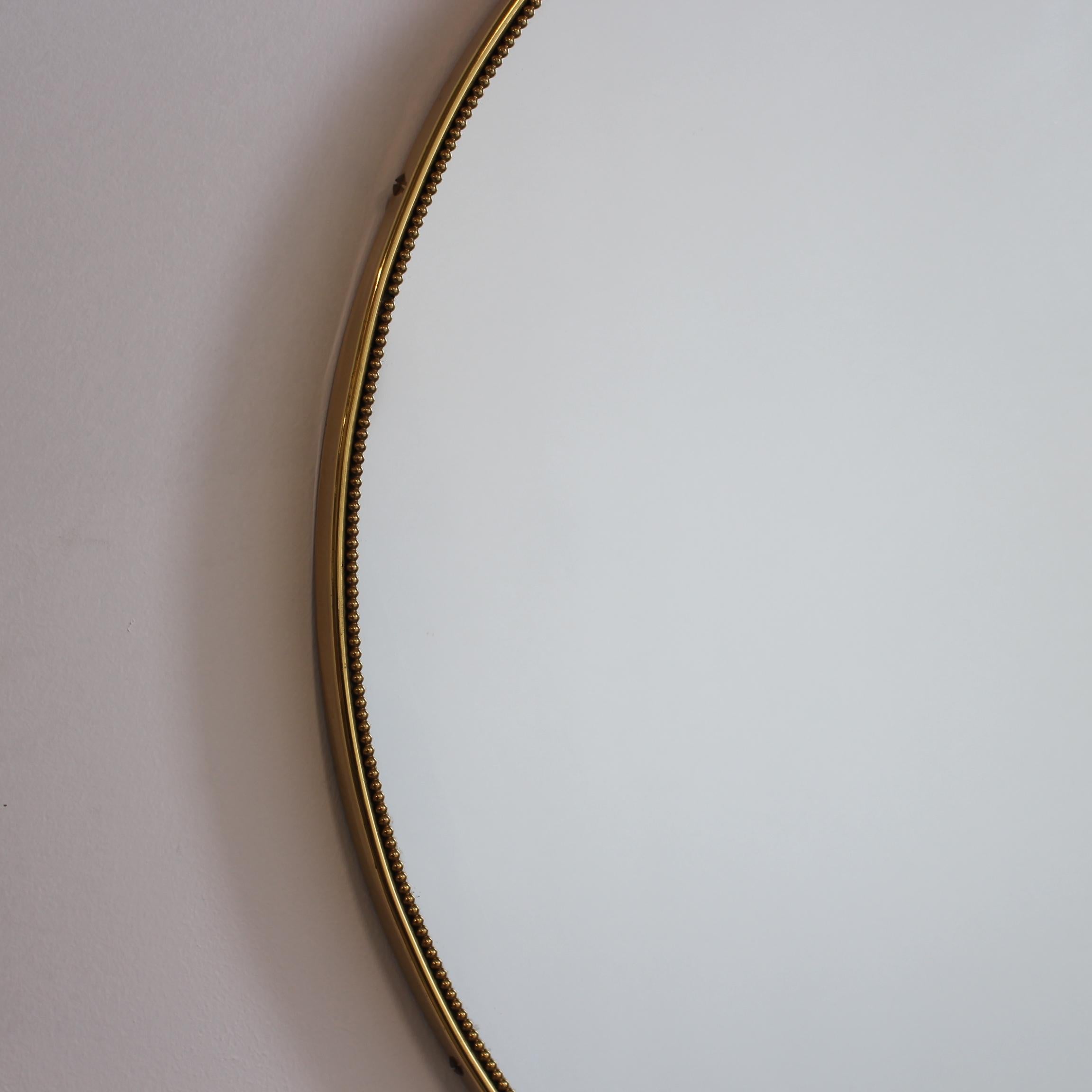 Miroir mural italien du milieu du siècle avec cadre en laiton (circa 1950s). Le miroir est de forme circulaire, très élégant et d'une durabilité irrésistible. L'impression visuelle est élégante et très unique dans le style moderne de Gio Ponti. Un