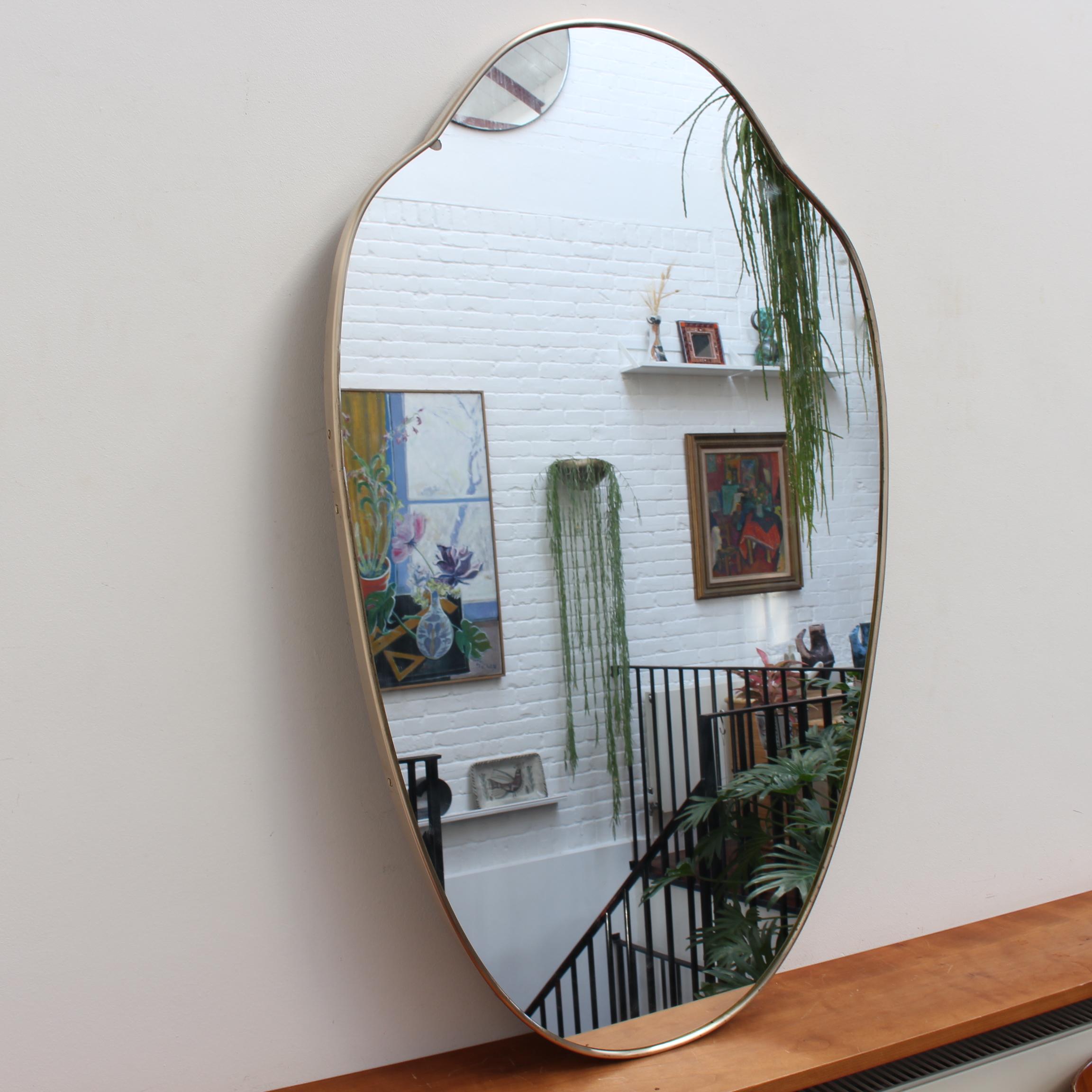 Mid-century Italian wall mirror with brass frame (circa 1950s). The mirror is classically-shaped and distinctive in a Modern style. It is in good overall condition with the exception of a small fault due to silvering in the upper left hand (see