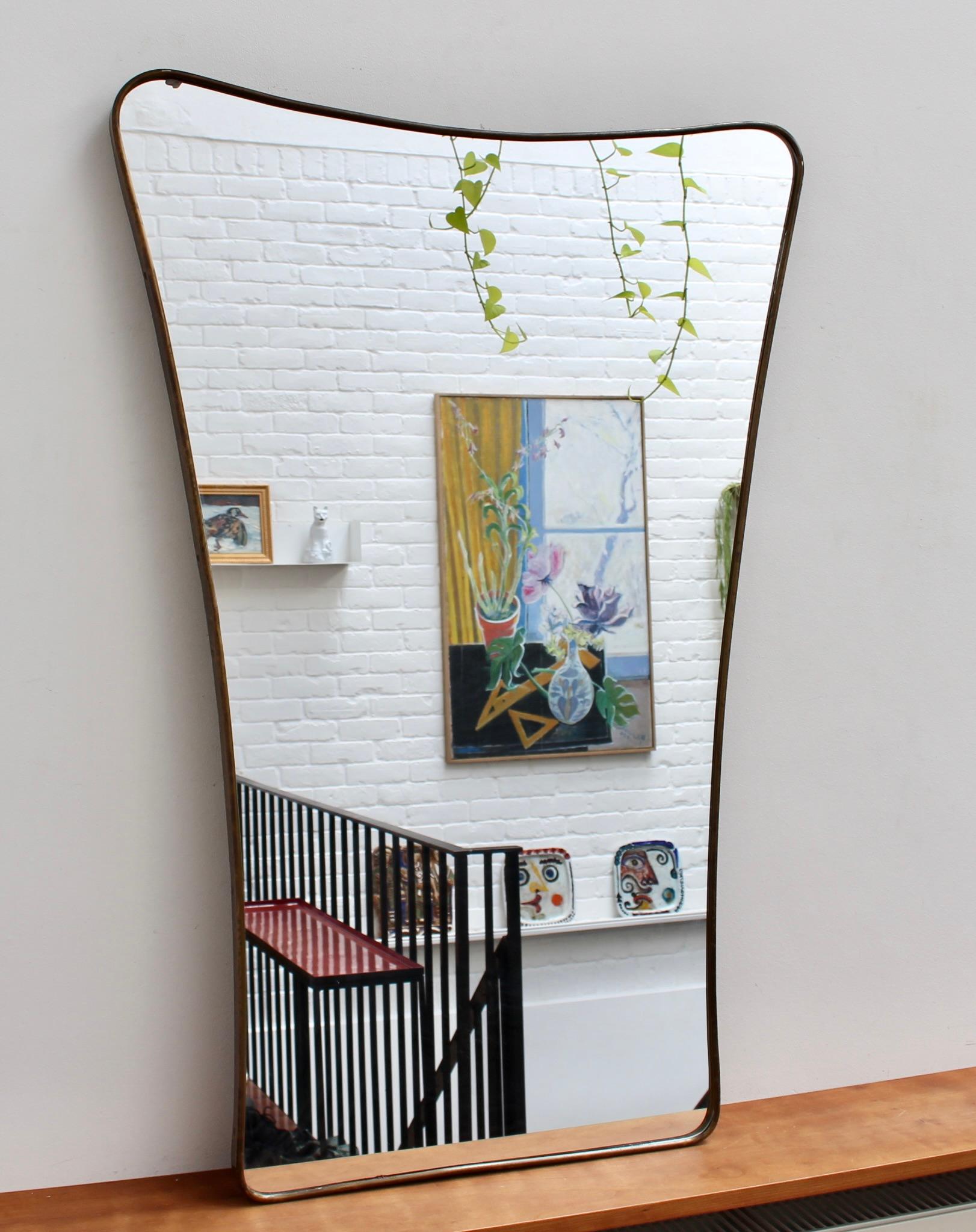 Mid-century Italian wall mirror with brass frame (circa 1950s). The mirror is classically-shaped and distinctive in a Modern style. It is in good overall condition with just a small blemish in the upper left hand adjacent to the frame. A beautiful