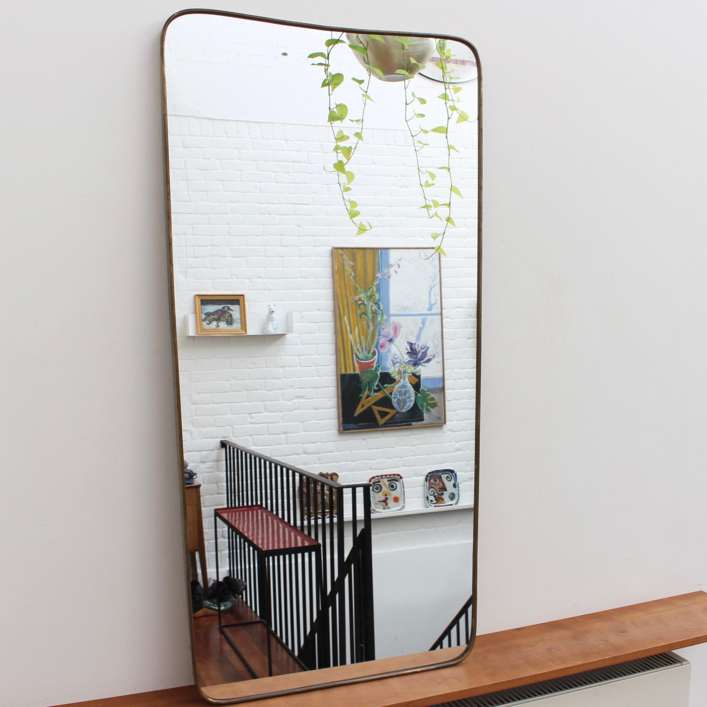 Mid-century large Italian wall mirror with brass frame (circa 1950s). The mirror is classically-shaped and distinctive in a Modern style. It is in good overall condition presenting just a small blemish in the glass giving it that extra vintage feel