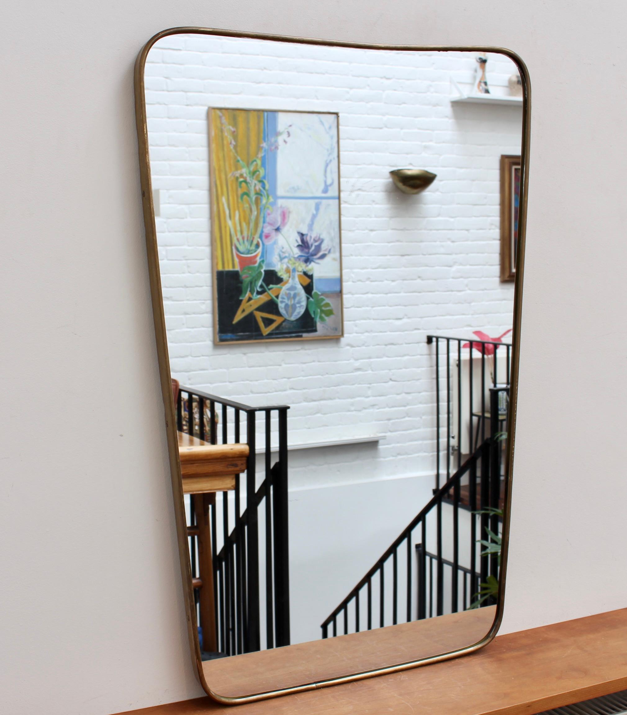 Vintage Italian Wall Mirror with Brass Frame (circa 1960s). The mirror is beautifully shaped and classically elegant in a modern Gio Ponti style. The piece is in overall good condition with an aged patina on the brass frame. There is some slight