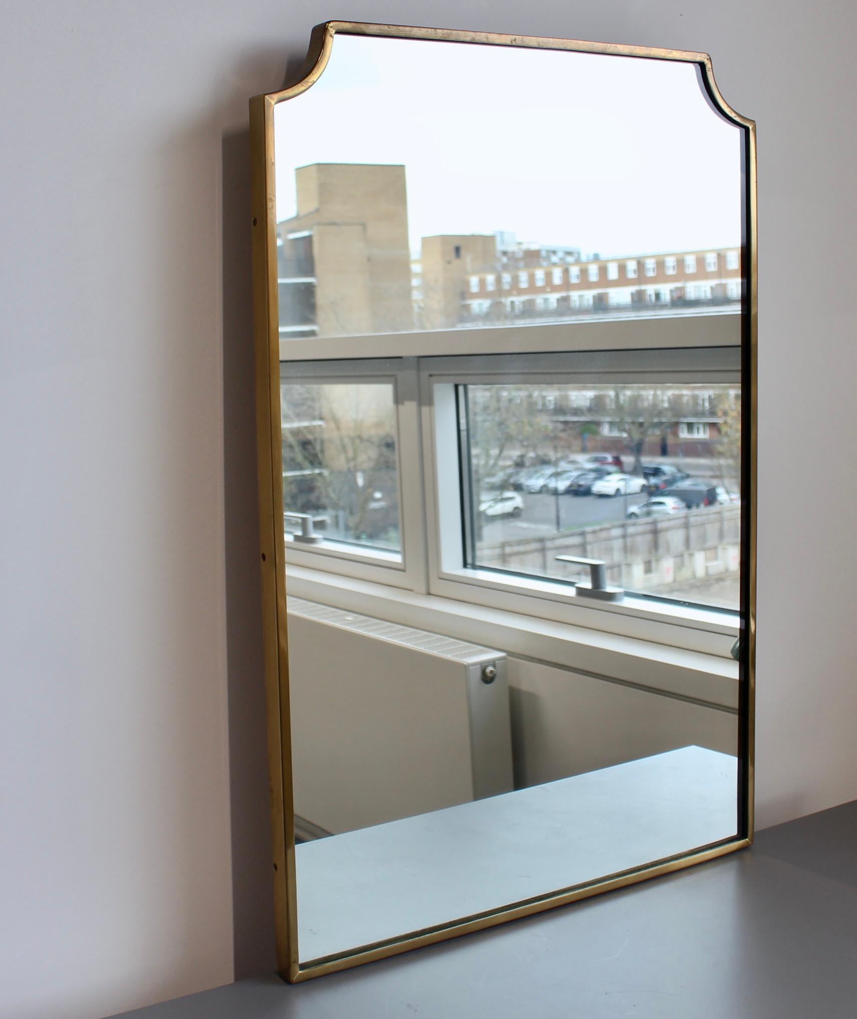 Specchio da parete vintage italiano con cornice in ottone (circa anni '60). Lo specchio è elegante e distintivo in un moderno stile Gio Ponti con una forma unica. Questo è in buone condizioni generali. La cornice presenta una caratteristica patina