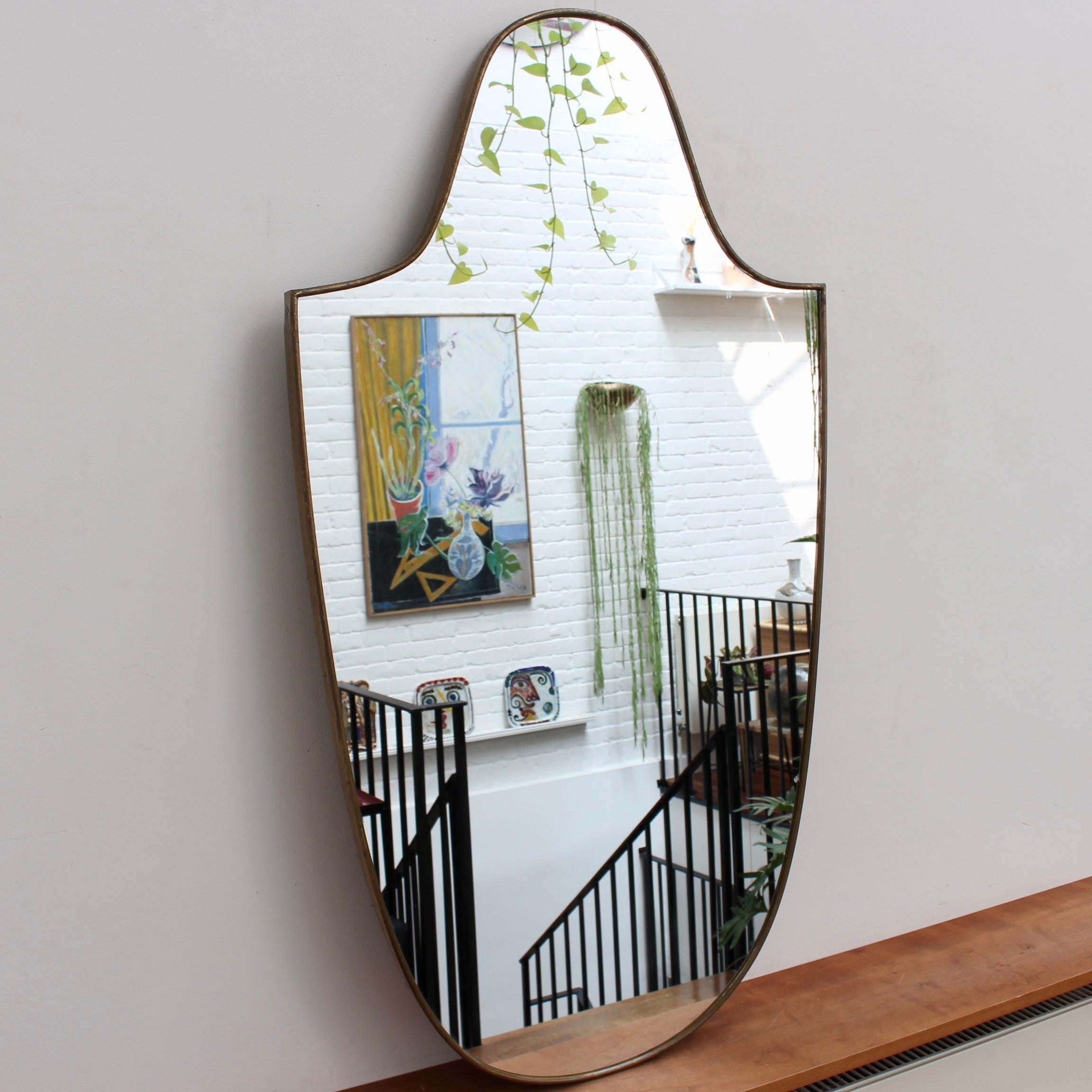 Mid-century Italian wall mirror with brass frame (circa 1950s). The mirror is classically-shaped and distinctive in a Modern style. It is in good overall condition with just a slight chip in the glass as seen in the photos accompanying the listing.