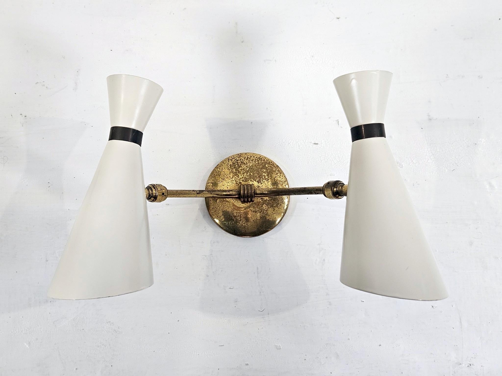 Aplique de pared de los años 50, blanco marfil y dorado, a la manera de Stilnovo Italia. Los dos conos de luz son ajustables en todos los ángulos. El revestimiento es nuevo y está en buen estado, y el latón se ha conservado tal cual, con signos de