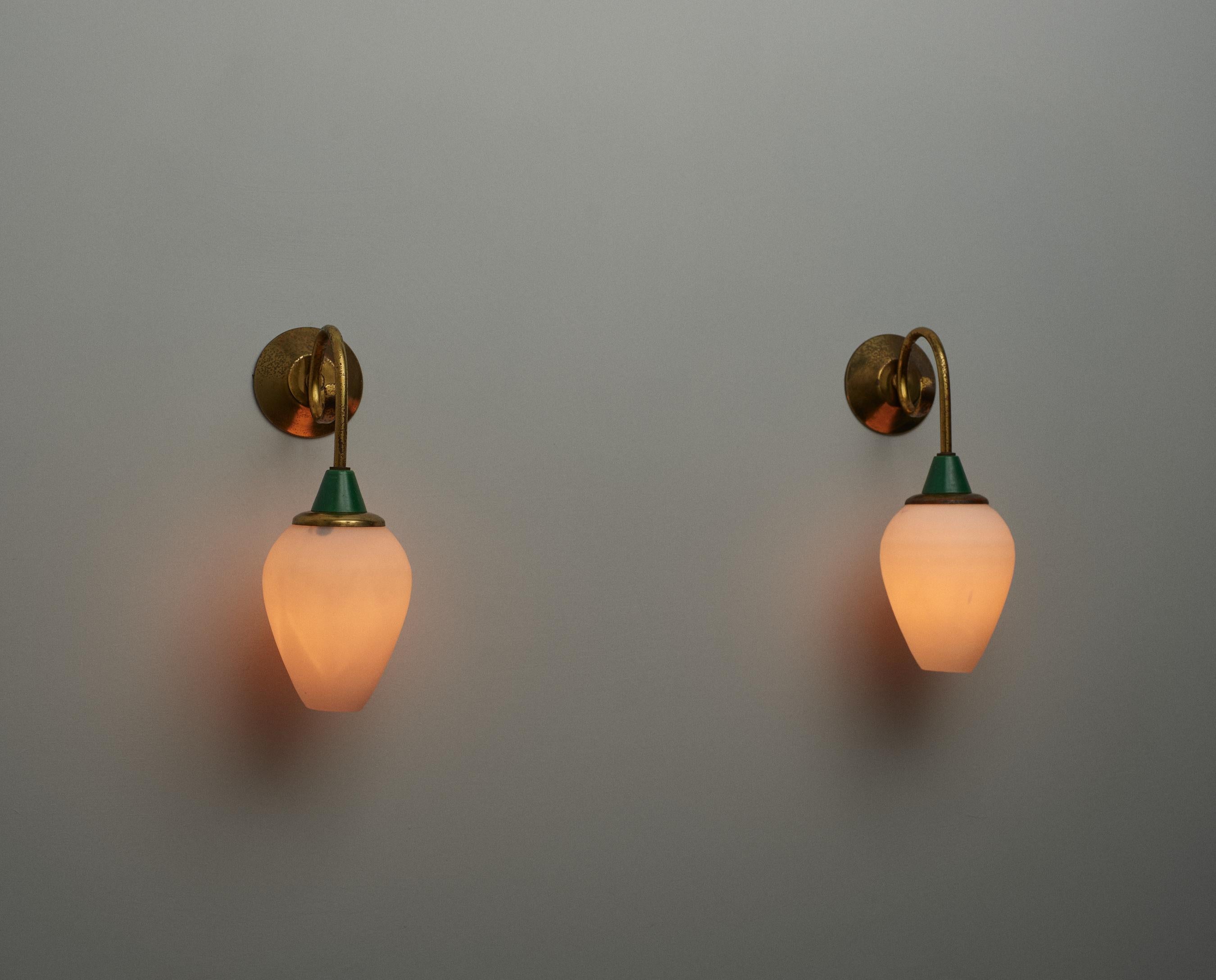 Diese in Italien in den 1950er Jahren gefertigten Wandleuchten aus der Mitte des Jahrhunderts spiegeln die moderne Eleganz der Epoche wider. Sie kombinieren robustes Messing mit Opalglasschirmen und markanten grün lackierten Metallakzenten. Jede