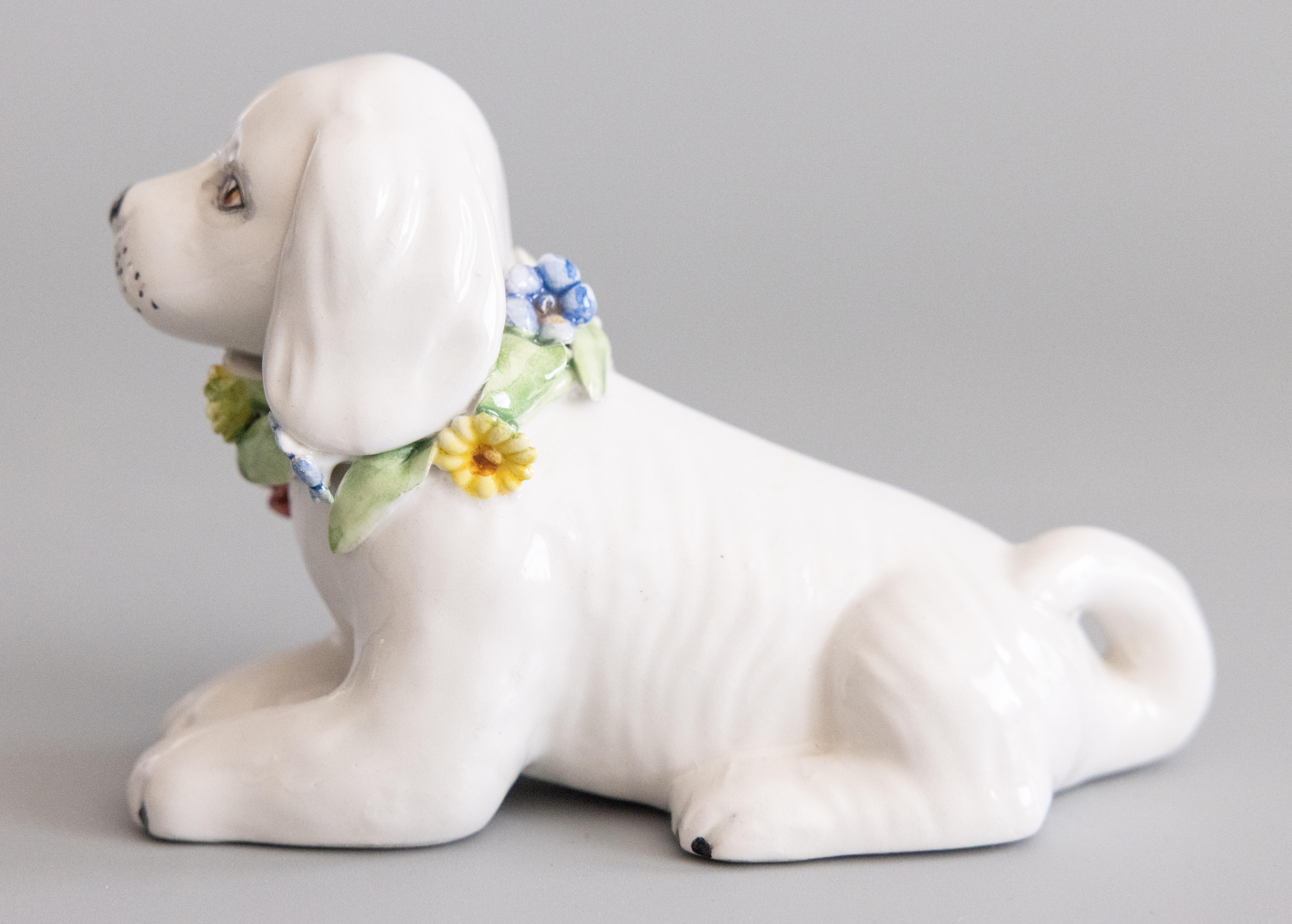 Un'incantevole statuetta di cane in maiolica bianca italiana d'epoca con una bella corona di fiori al collo, circa 1950. Marcato 