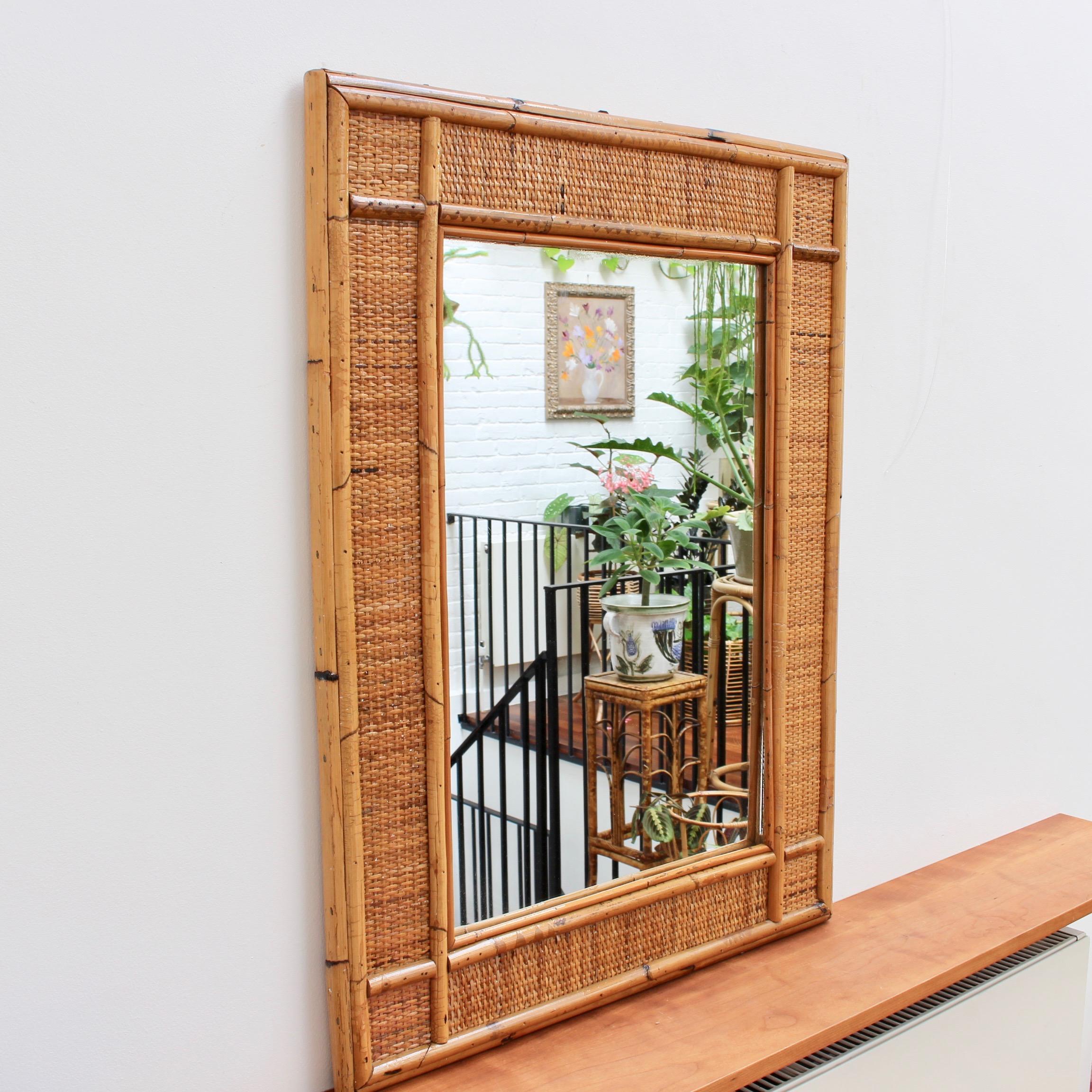 Midcentury Italian wicker and rattan wall mirror (circa 1960s). This mirror has a delightful rectangular shape with glass enclosed by the caned frame which is itself, framed by wicker and more cane. The wicker In between the two frames is a