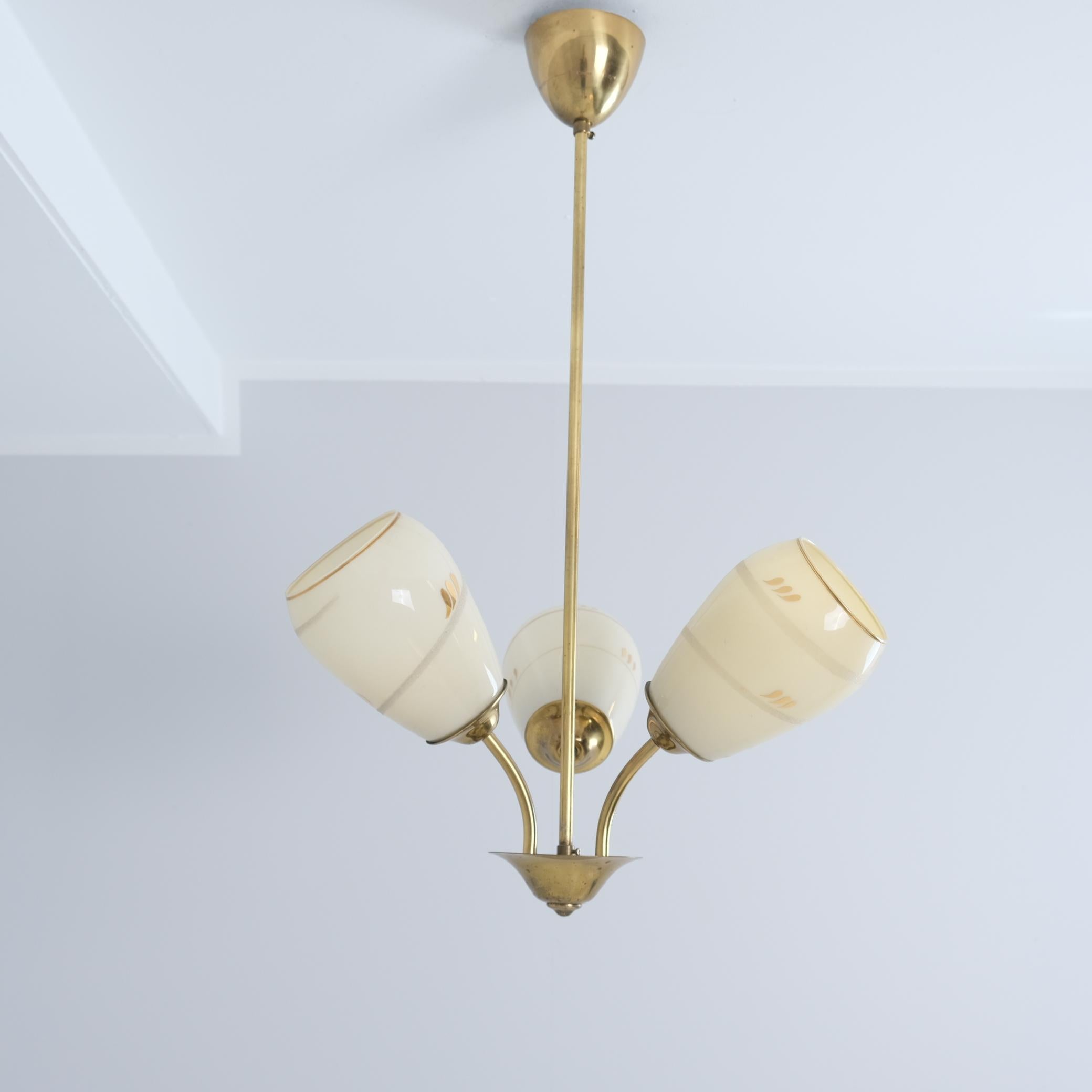 Una bellissima e delicata lampada da soffitto finlandese di metà secolo, modello ER 86/3 di Itsu, uno dei principali produttori di illuminazione della Finlandia. La lampada presenta tre basi luminose con paralumi in vetro opalino dipinto a mano.