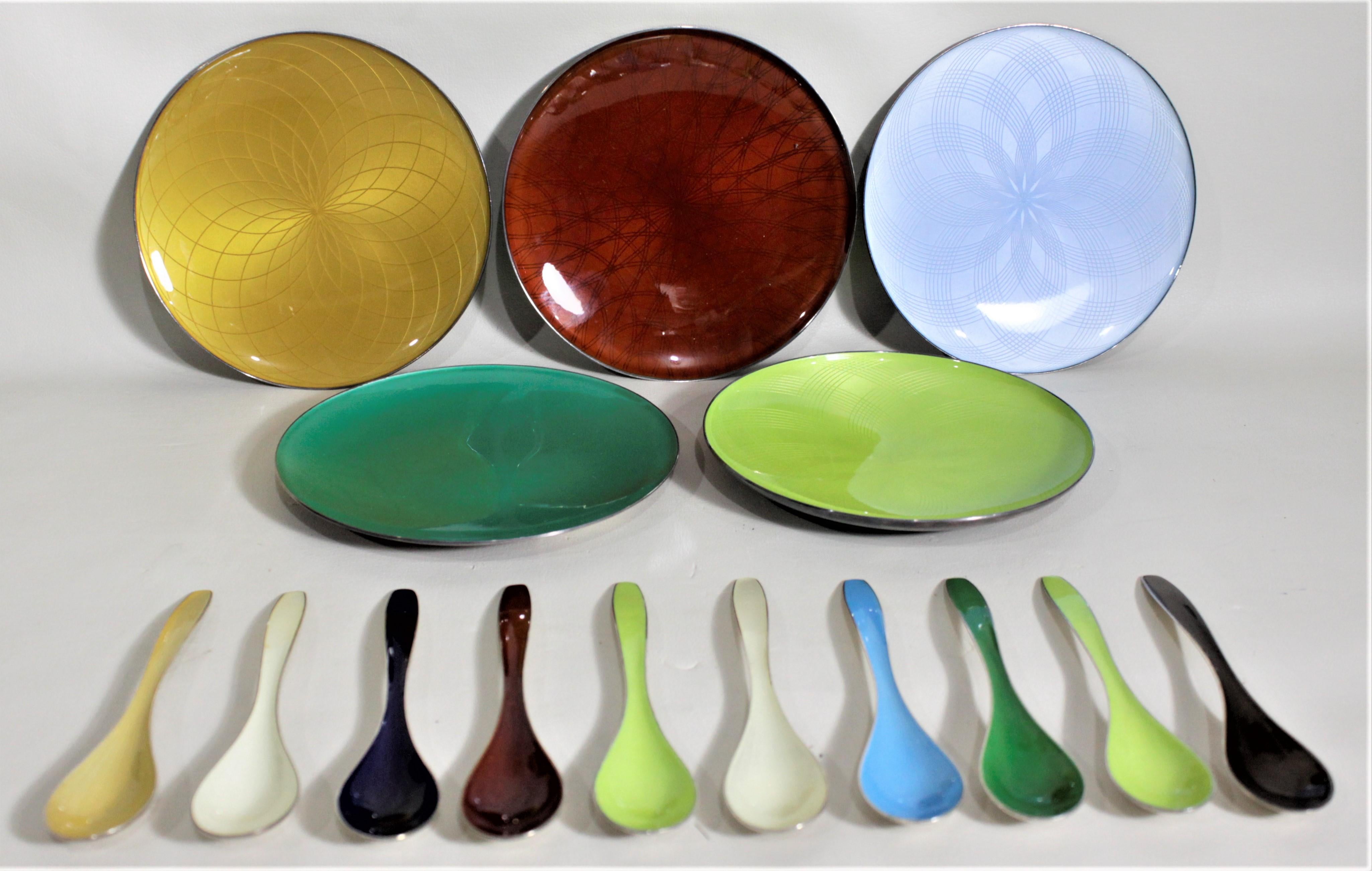 This set of ten enameled sterling silver spoons and five enameled sterling silver plates were made by J. Tostrup of Norway in circa 1970, in the Mid-Century Modern style. The five serving plates, or shallow bowls, are of differing vibrant colors and