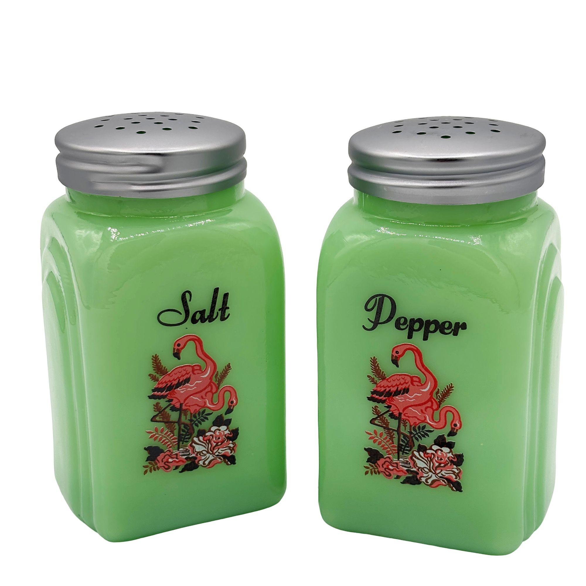 Set di sale e pepe in vetro verde giadeite di metà secolo con fenicotteri rosa sul davanti. Ogni shaker presenta una coppia di bellissimi fenicotteri rosa tropicali in piedi tra deliziosi fiori di ibisco, con un motivo ad arco romano stampato sui