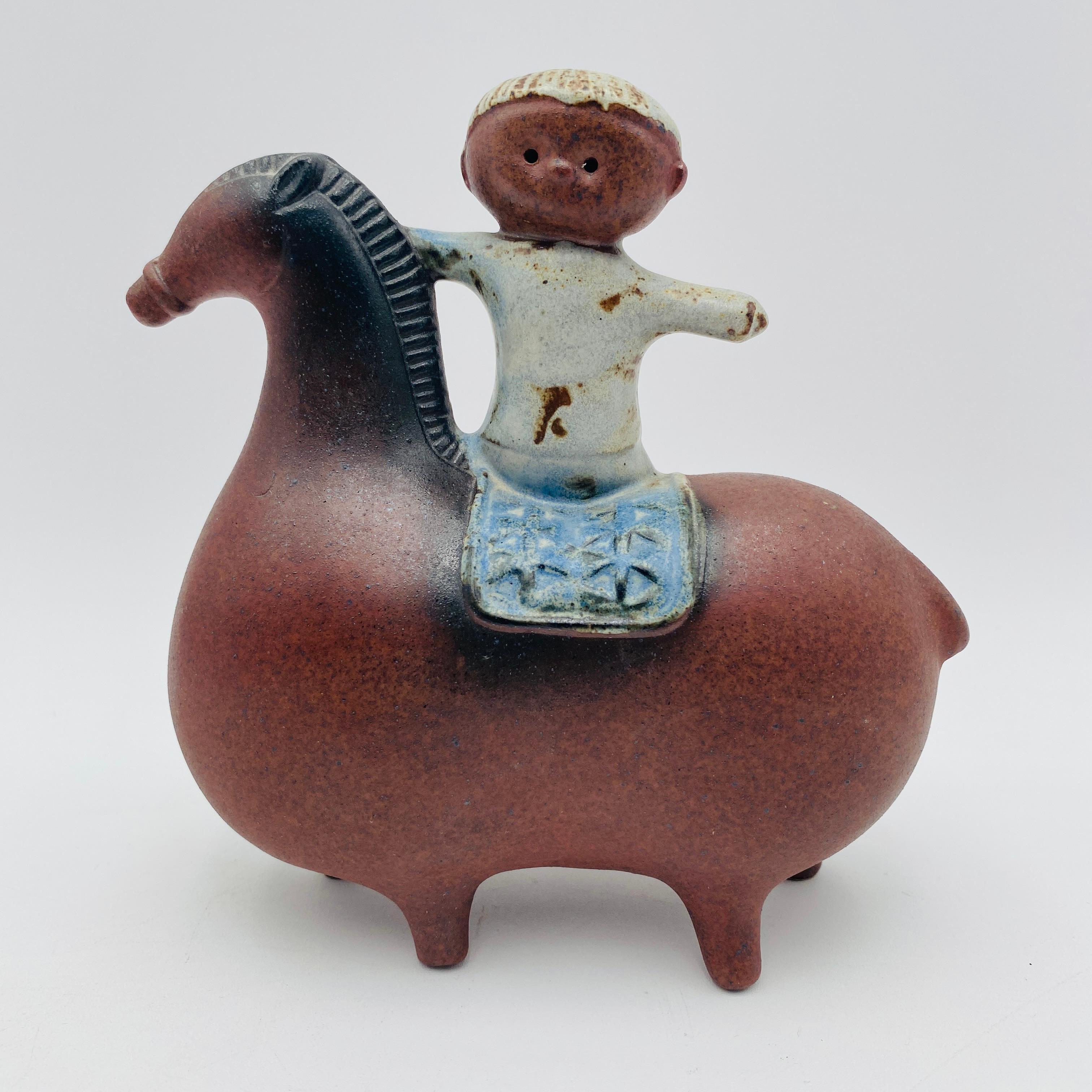 This Mid Century art pottery figurine of a boy on a horse has been attributed to both Lisa Larson and Stig Lindberg. The horse is in the style of Lindberg, who exaggerated the proportion of their bodies relative to their heads. The figurine of a boy