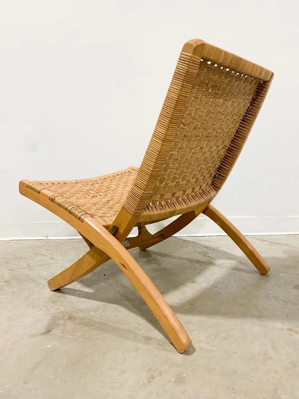 Rare folding lounge chair with cane seat and back made by Kosuga of Japan. High-quality build and beautiful woven cane combine for an exercise in sublime minimalism. Folds up easily for storage or to be hung on the wall. This chair is in very good