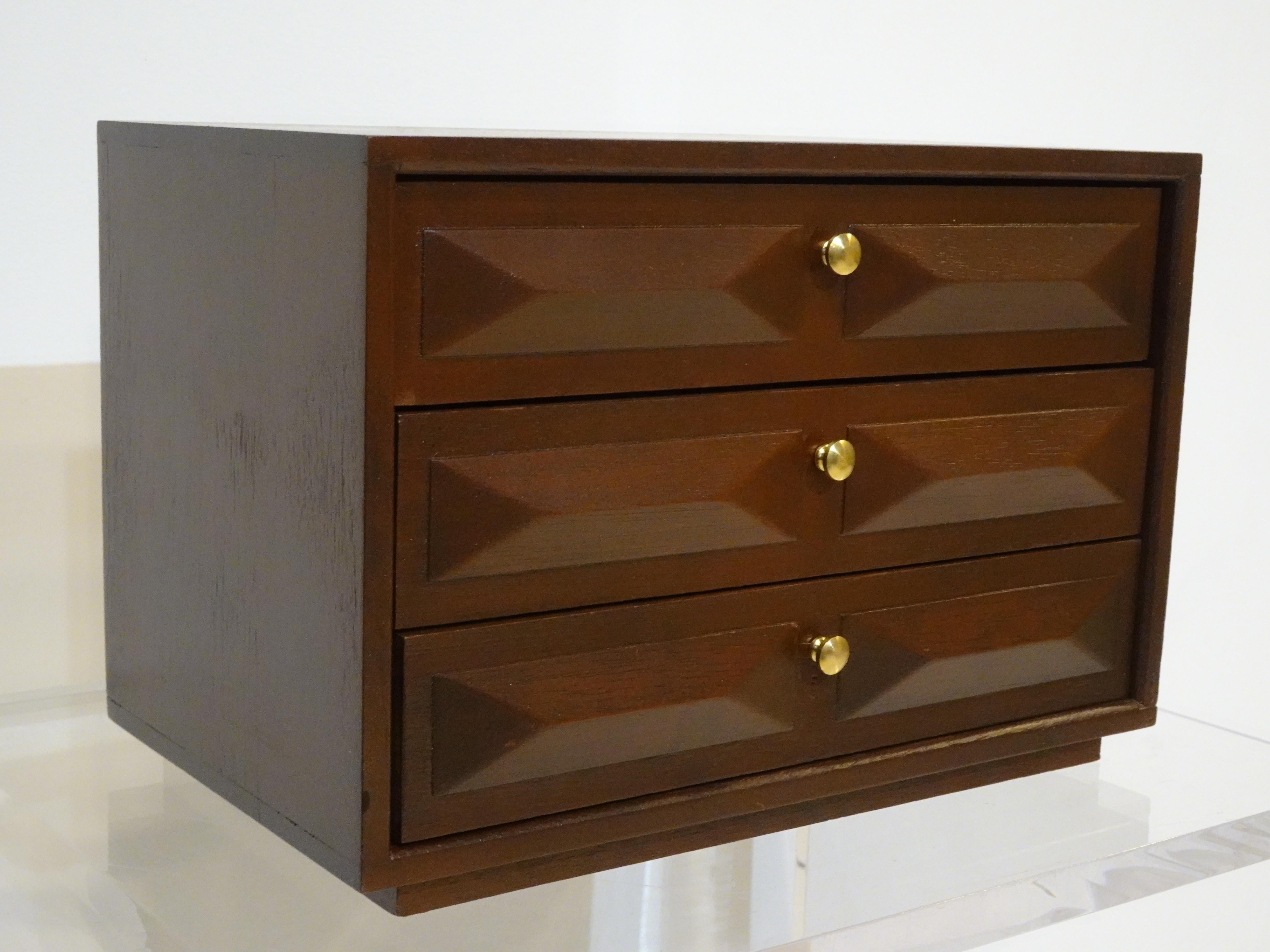 A dark walnut toned three drawer jewelry box with brass pulls the top drawer having six divided compartments the second has four compartments and the bottom is just a large one . All covered in a cranberry felt and would very well for your everyday