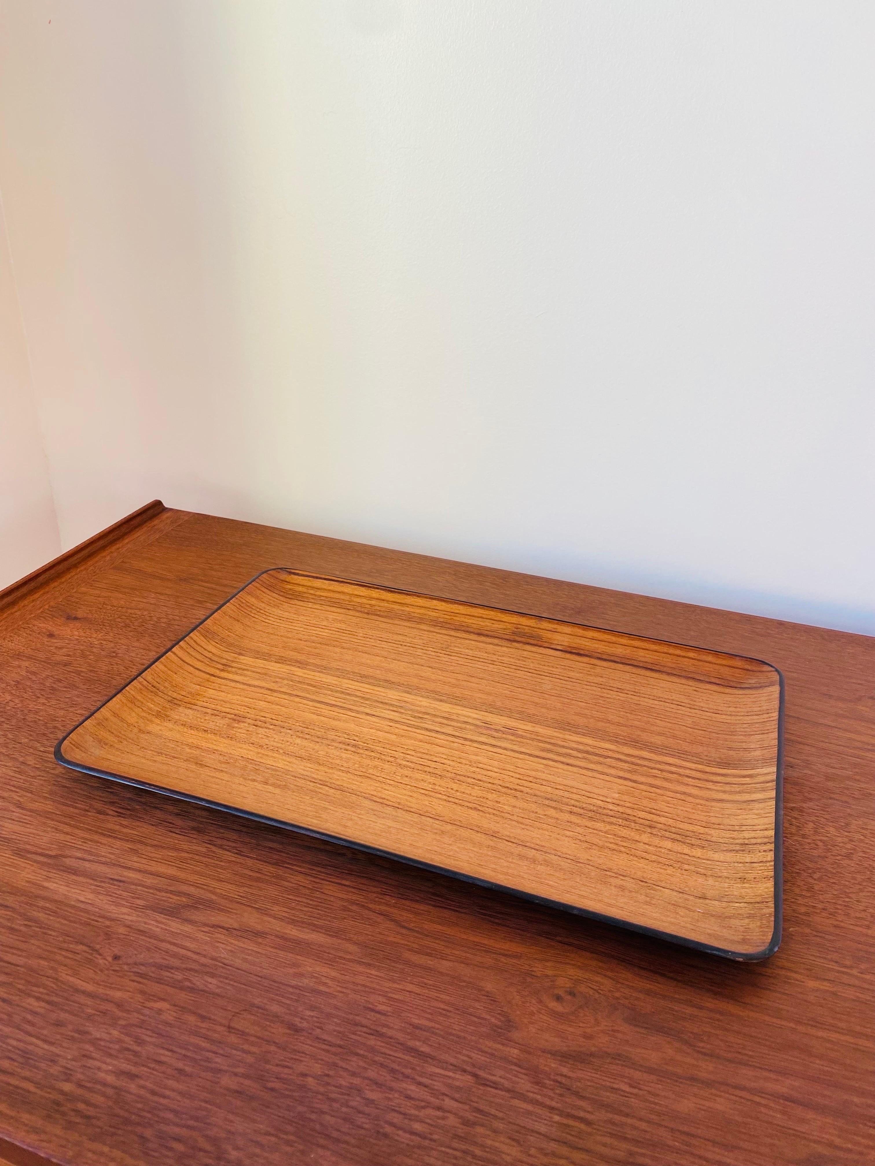 Preciosa bandeja vintage de teca japonesa con impresionantes vetas de madera. Diseño minimalista lleno de estilo.  La veta de la teca envuelve la superficie de la bandeja y la base es de color negro mate. 

Un diseño excelente que combinaría bien