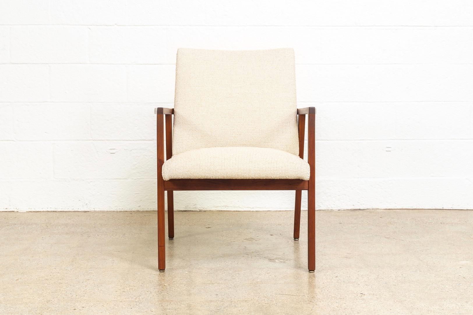 This vintage Mid-Century Modern Jens Risom lounge armchairmanufactured by DoMore Corporation is circa 1960. The Minimalist, Danish modern design features a rich, solid walnut wood angular frame with beautiful sculpted armrests. The chair has been