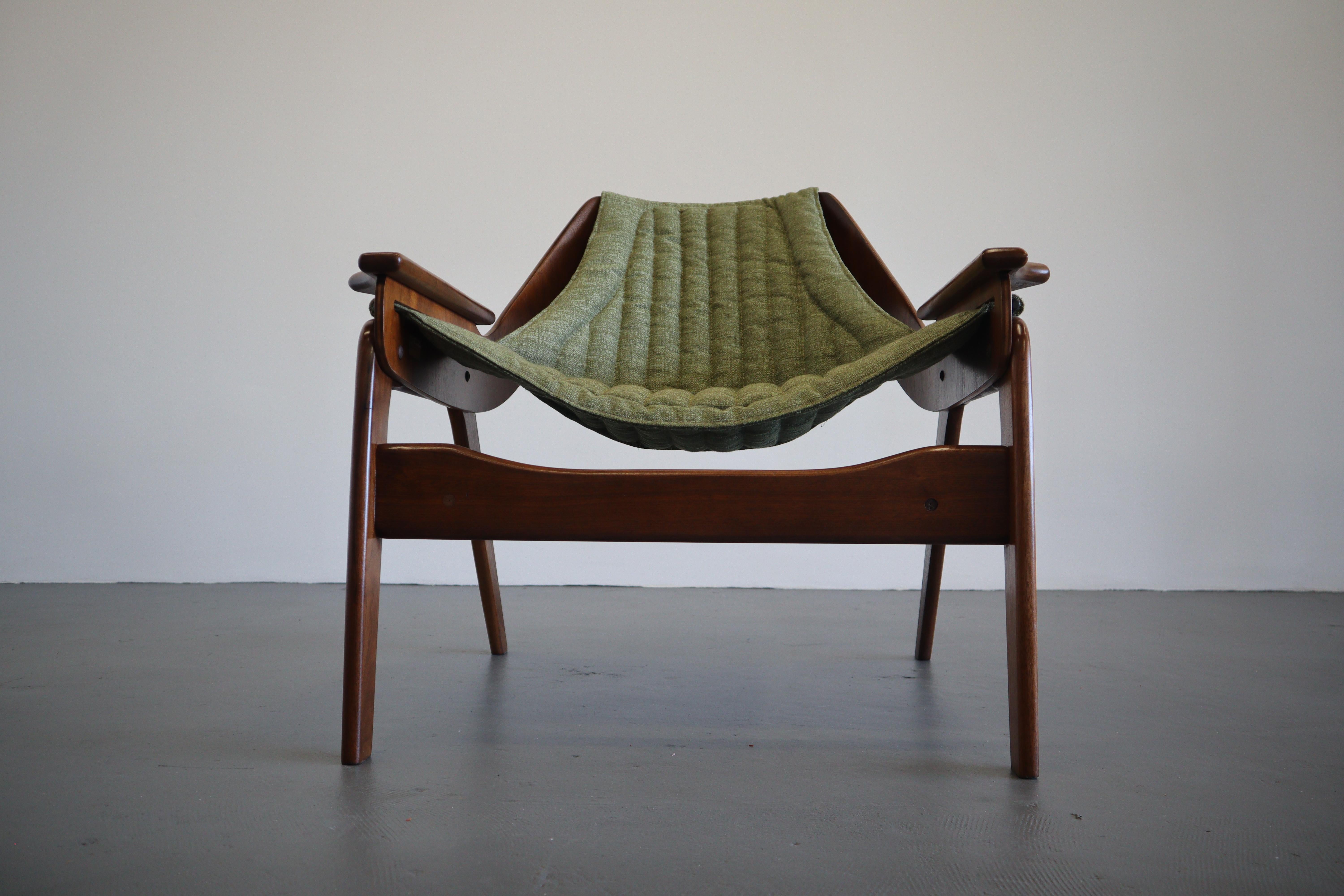A sturdy walnut frame with a sculptural concave back rest, this mid-century marvel is designed by Jerry Johnson. The olive channeled tweed sling design is well suited for lounging and relaxation. Substantial base with angled legs and oversized plugs