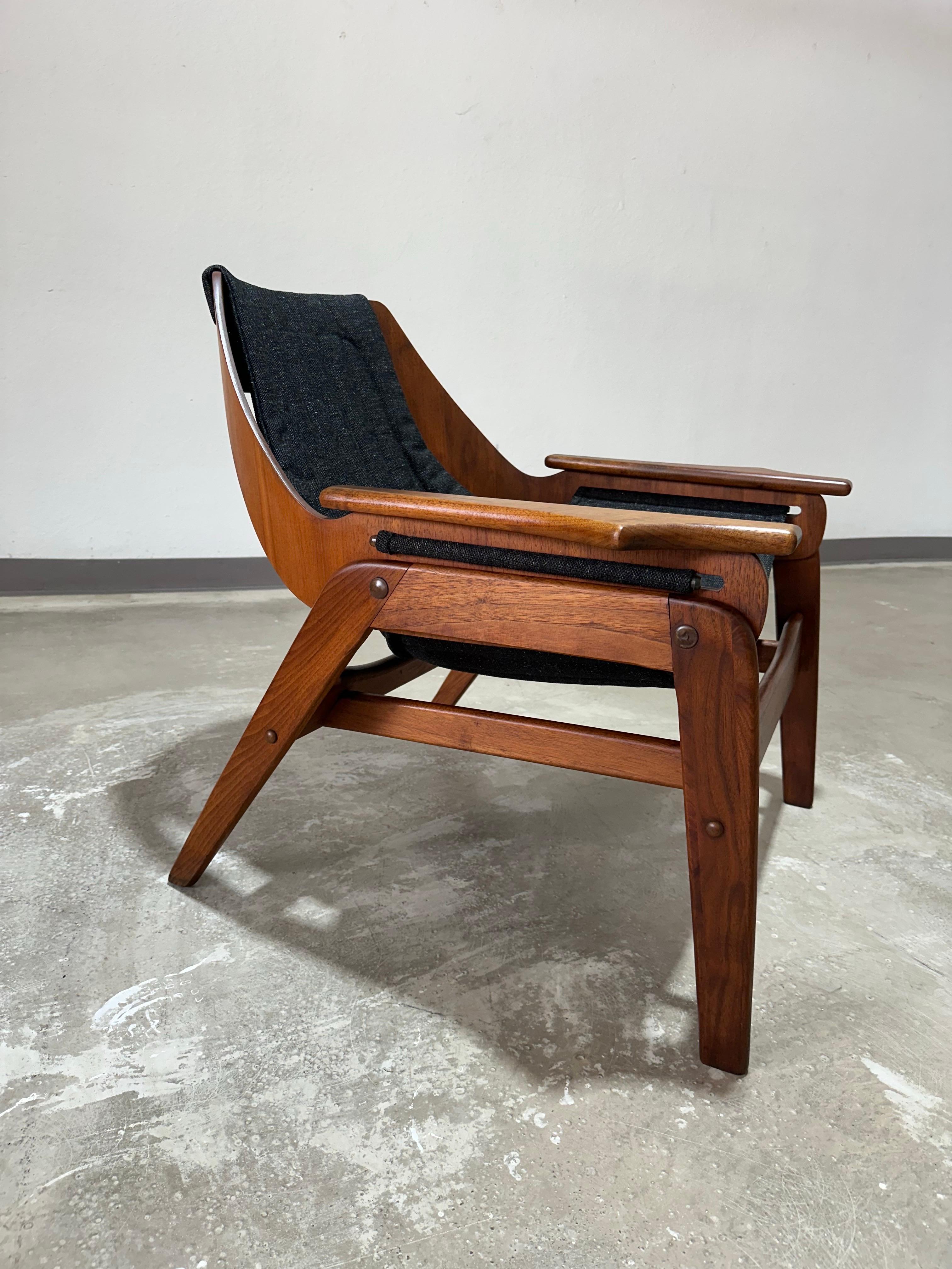 Jerry Johnson Triumph Sling Chair in Walnut and channel tufted black fabric sling. Designed by California designer Jerry Johnson in the Unique patented three-point suspension construction. Frame is molded of walnut in hand-rubbed oil finish, with
