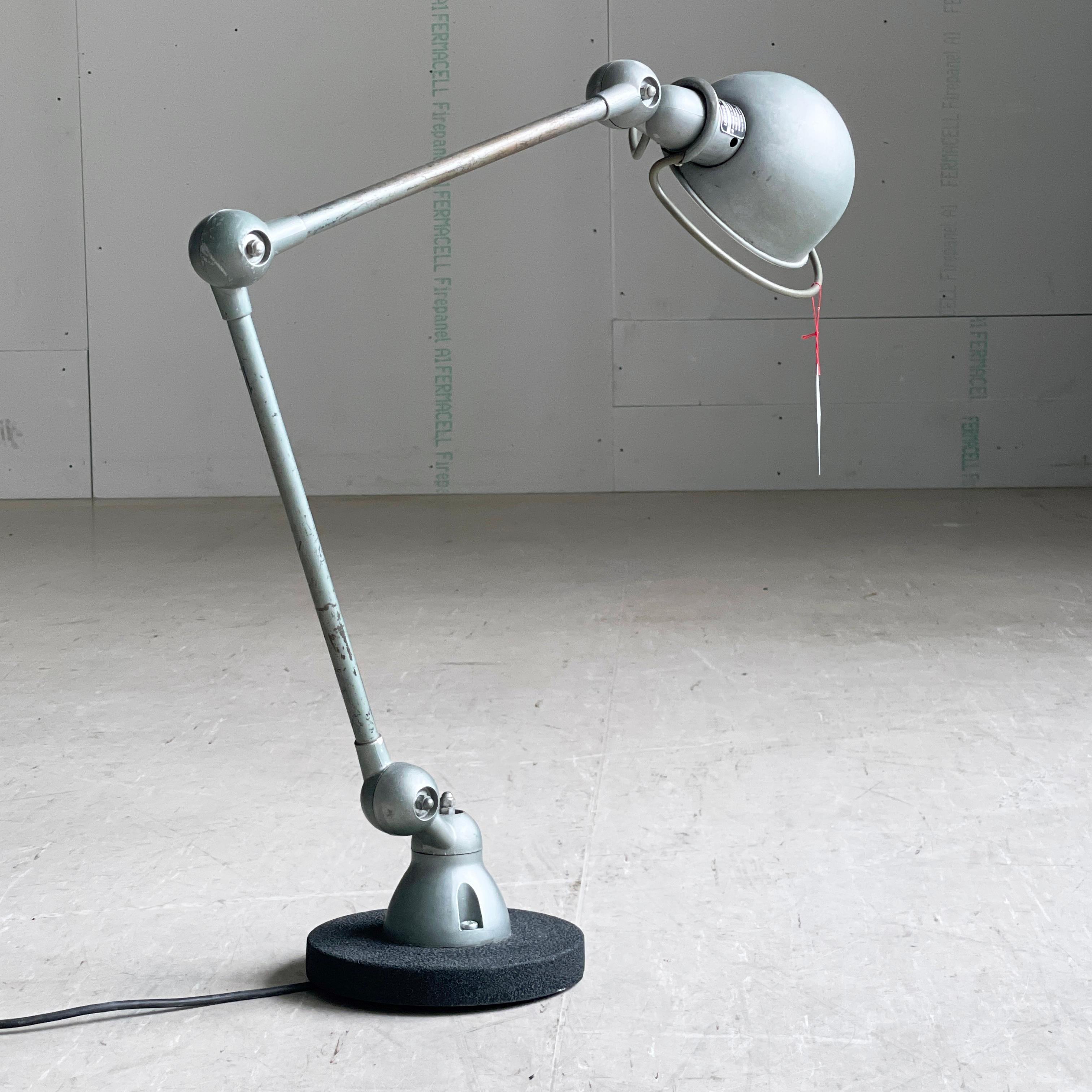 JIELDÉ 1950’s INDUSTRIAL DESK / TABLE LAMP 
Designer: Jean Louis Domecq, 1950’s. Double arm on heavy wrought iron base.
Produced: Jieldé, France
On/Off switch on lampshade. Swiss wall plug.
In a metallic geen/grey colour which would easily fit in
