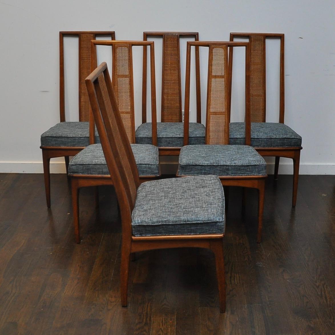 Clean set of 6 Mid-Century Modern walnut cane-backed dining chairs with new upholstery. Upholstery is made up of shades of light and dark blue and black.