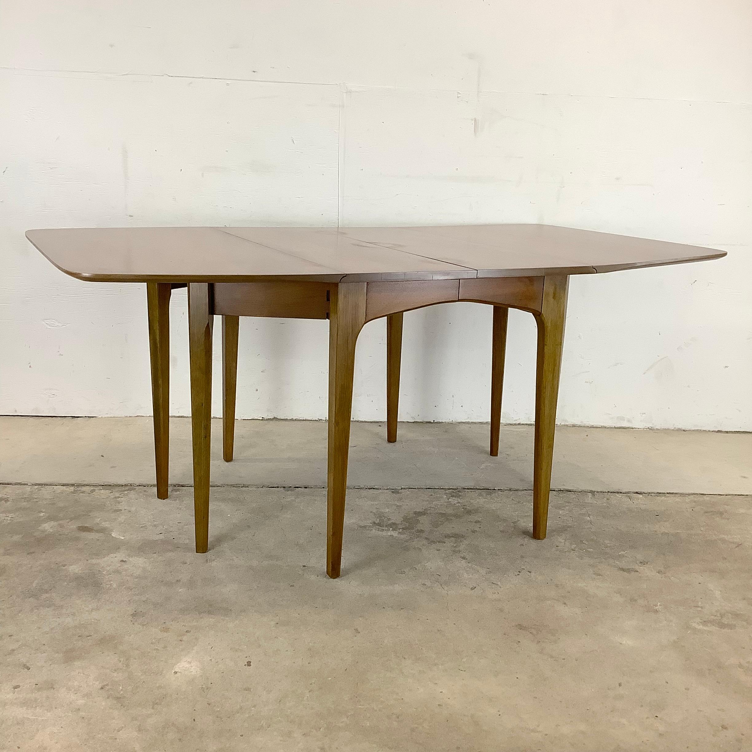 The John Van Koert for Drexel Mid-Century Walnut Drop-Leaf Dining Table is a versatile and timeless piece of furniture. This dining table combines Mid-Century Modern design, functionality, and exceptional craftsmanship to elevate your dining