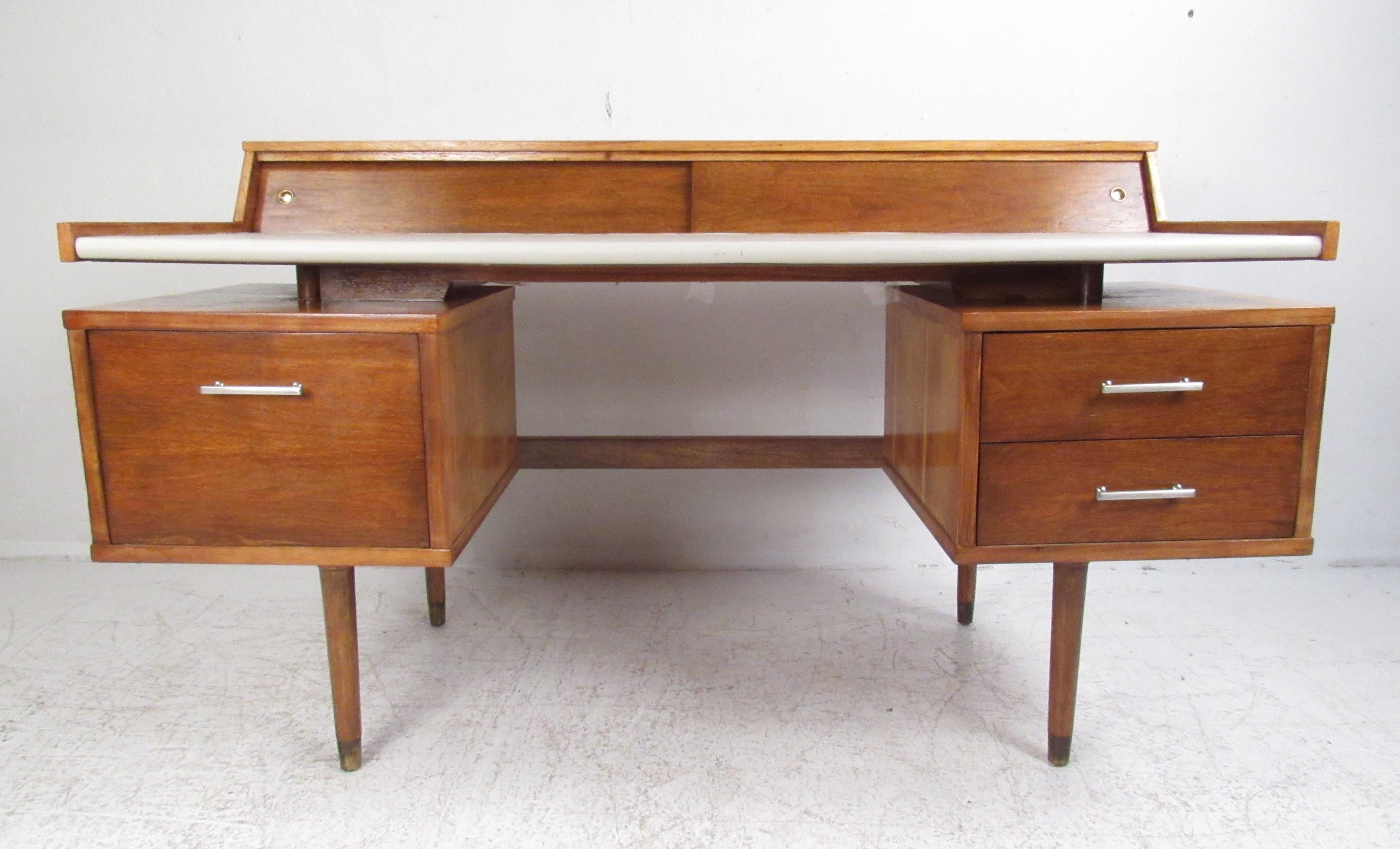This stunning vintage modern floating top desk features a large white vinyl work space and plenty of room for storage. A stylish walnut writing desk by John Van Koert with a sliding door on top hiding small storage compartments. The sculpted design,