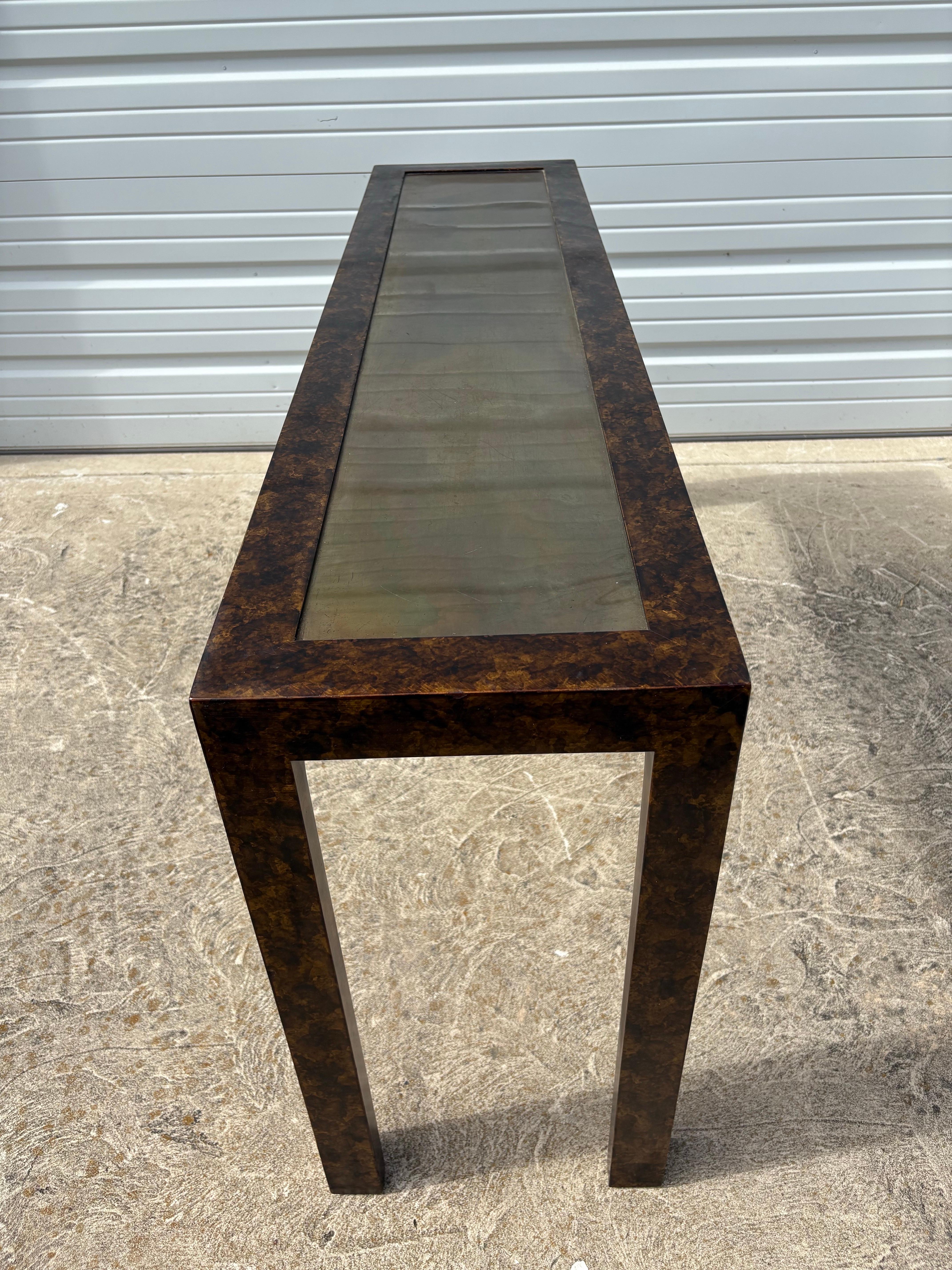 Il s'agit d'une élégante console vintage du milieu du siècle, réalisée par John Widdicomb . Cette console présente une riche finition en fausse écaille de tortue à la surface et un insert en laiton au centre. L'insert en laiton au centre présente