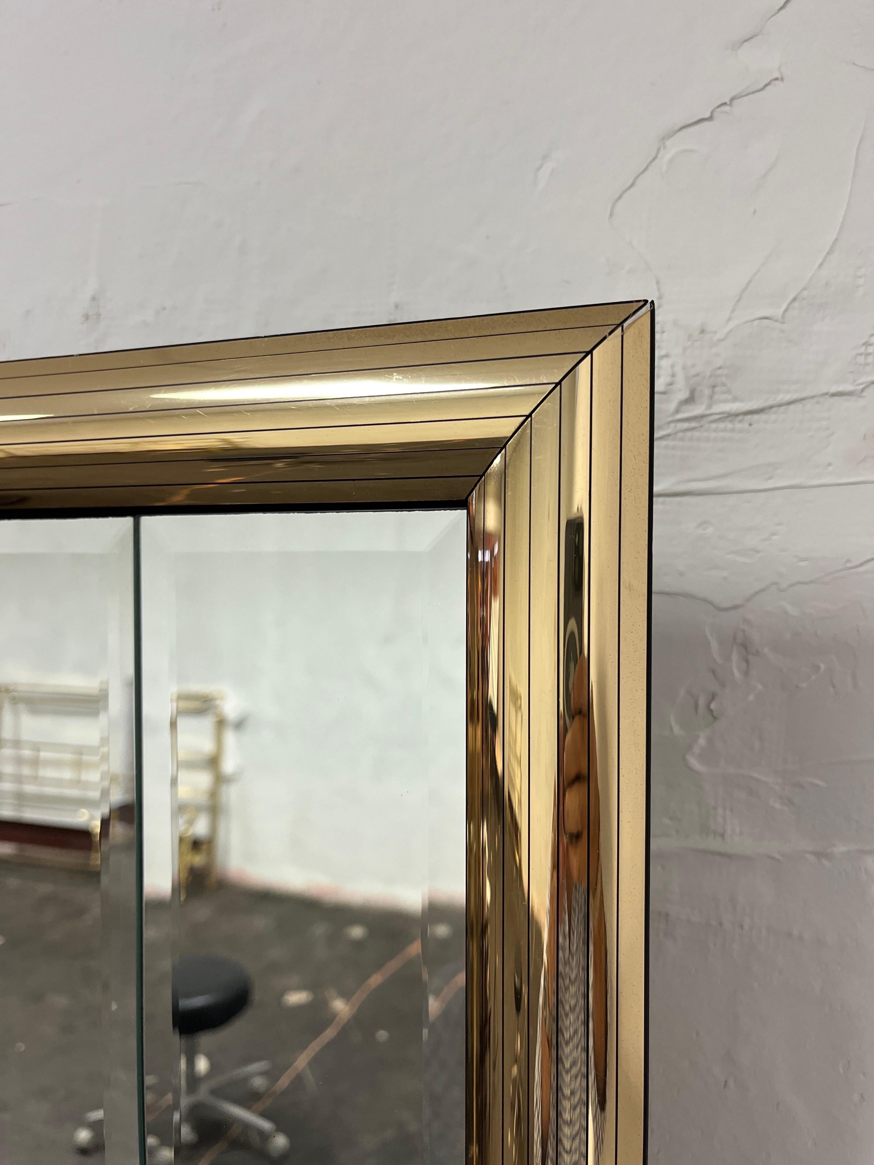 Unique mirrored shadowbox display mirror in the manner of Jon Gilmore. Signature gold mirrored strips in a bullnose beveled frame. Recessed mirror backdrop with 6 gold trimmed display shelves. 
Curbside to NYC/Philly $400