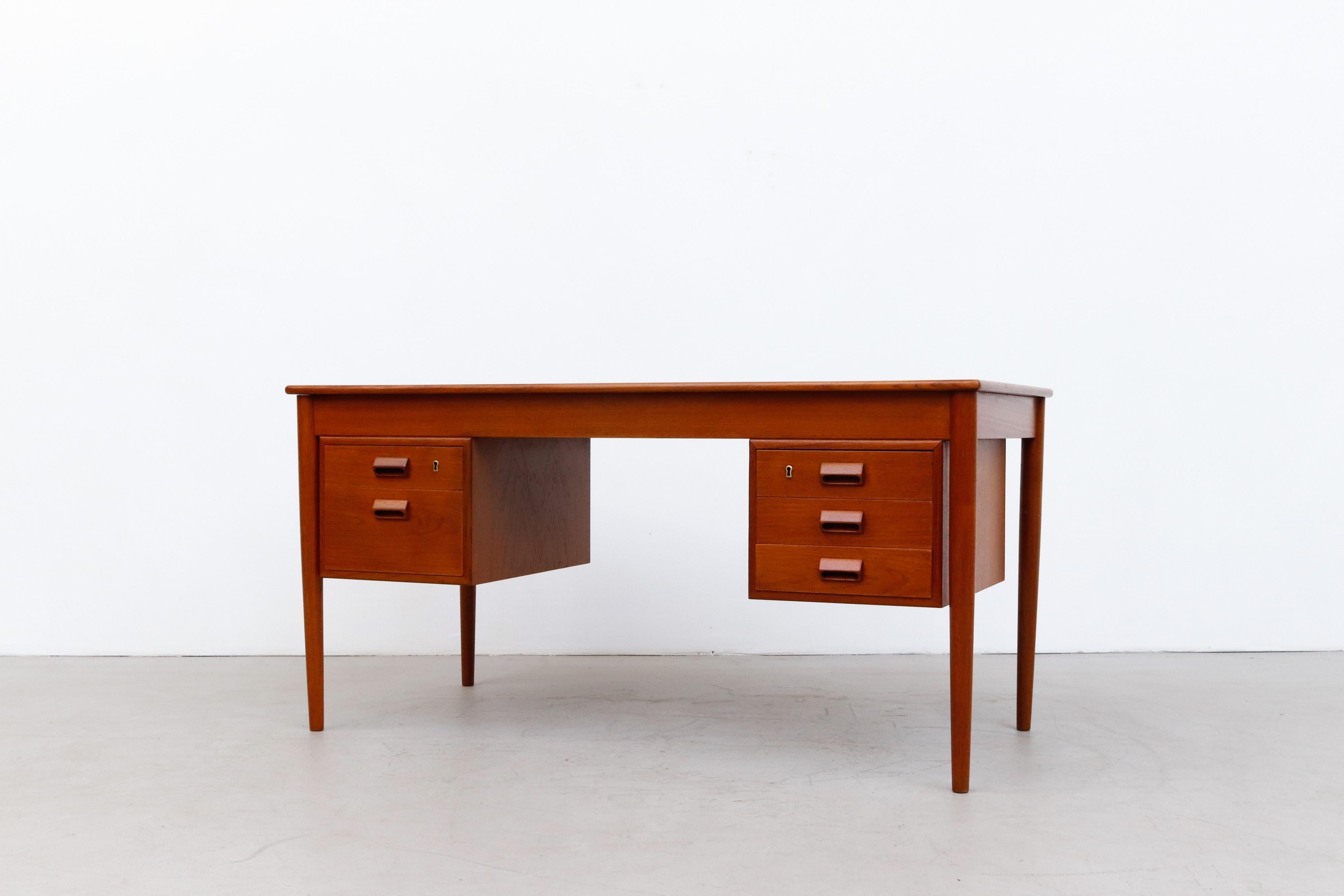 Gorgeous mid-century Danish teak desk by Kai Kristiansen with two sets of stacked drawers and slightly tapered legs. Lightly refinished in otherwise good original condition with key and minimal wear consistent with age and use.