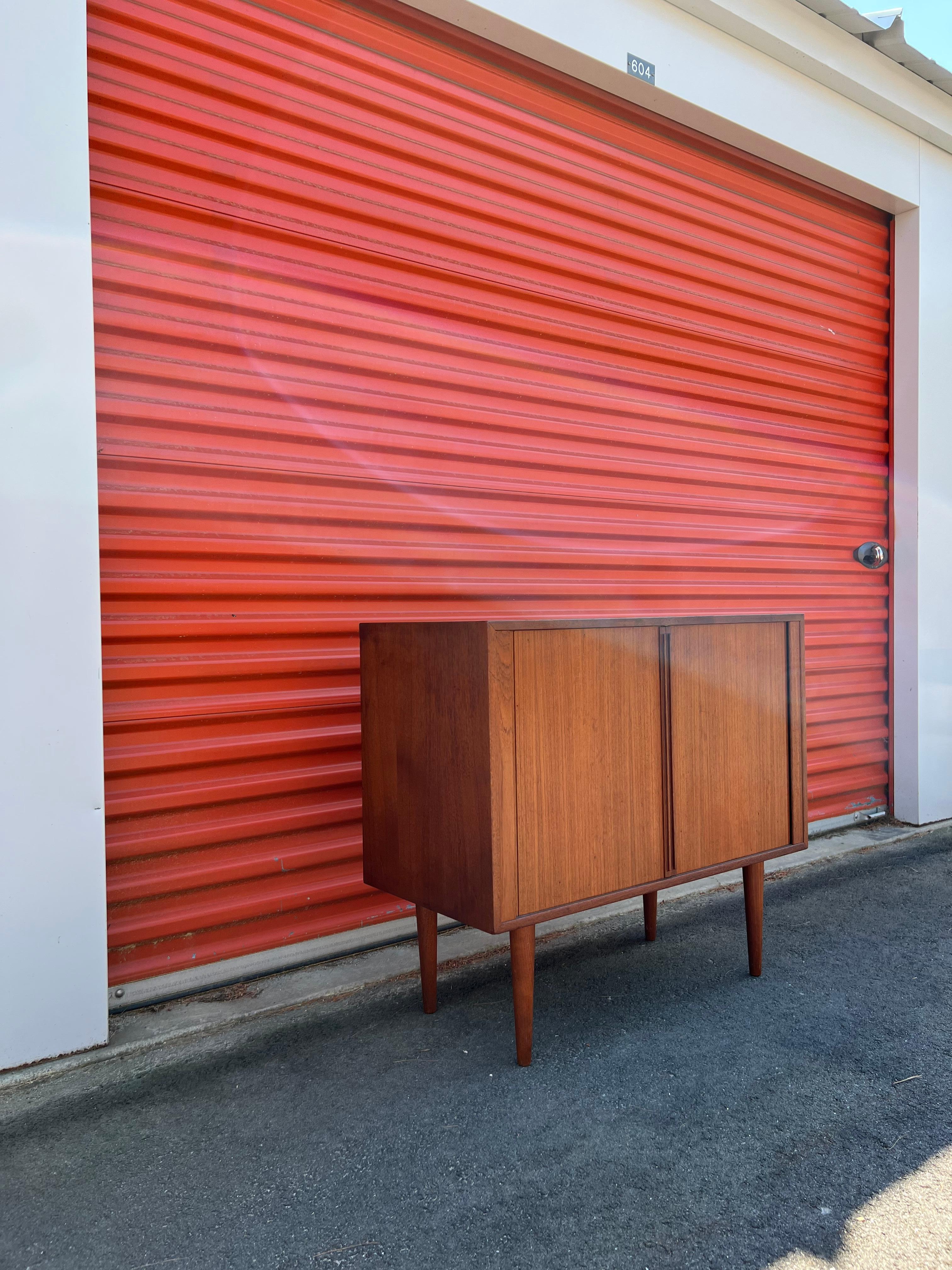 Stylish and compact teak cabinet designed in the 1960s by Kai Kristiansen for Feldballes Møbelfabrik of Denmark.
The two tambour doors with elongated, recessed pulls open to reveal seven sections for records with built-in dividers above two