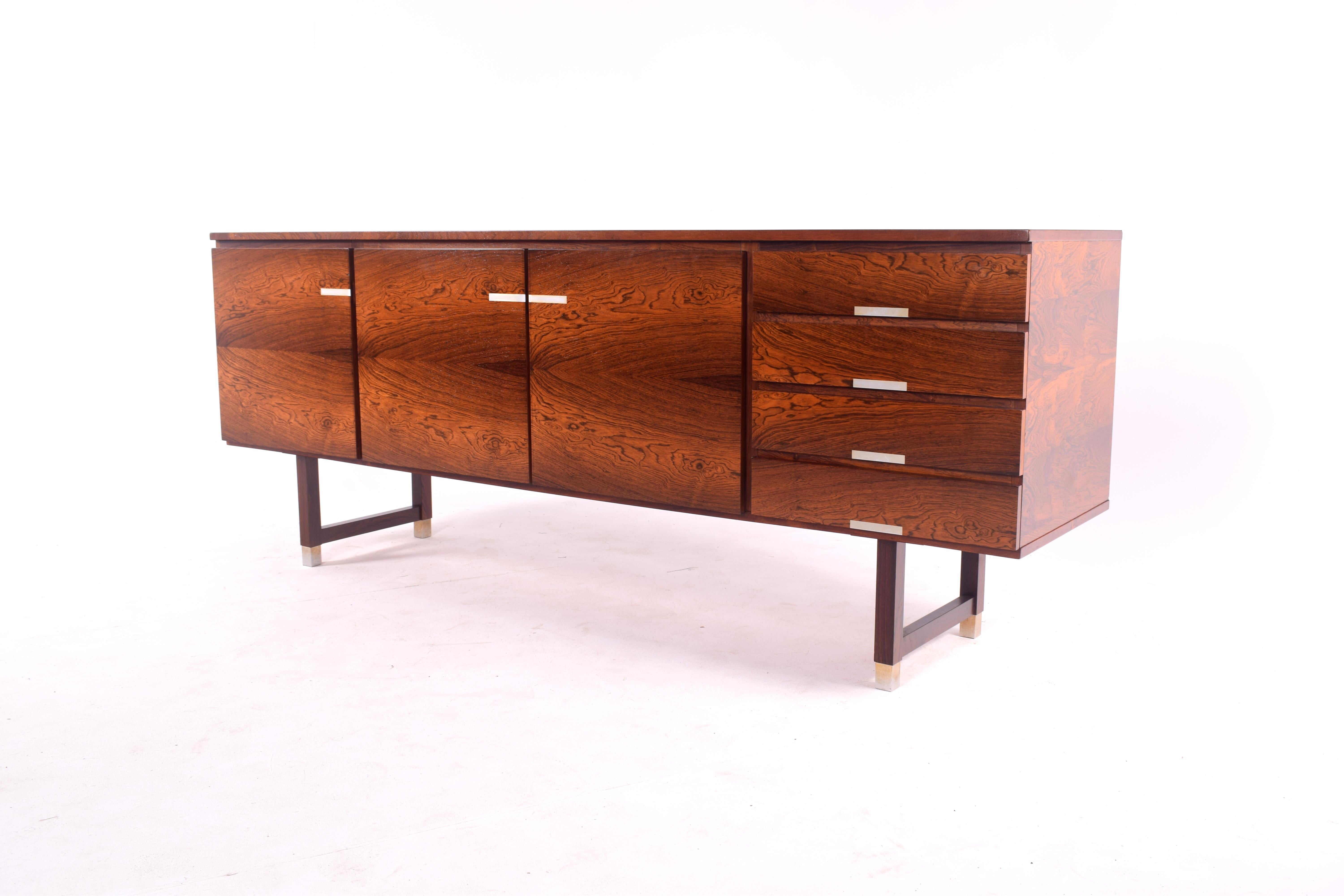 Nice rosewood sideboard. Features a horizontal book match grain on doors with contrasting aluminum inlay on handles. Raised on square legs with capped feet of aluminum.