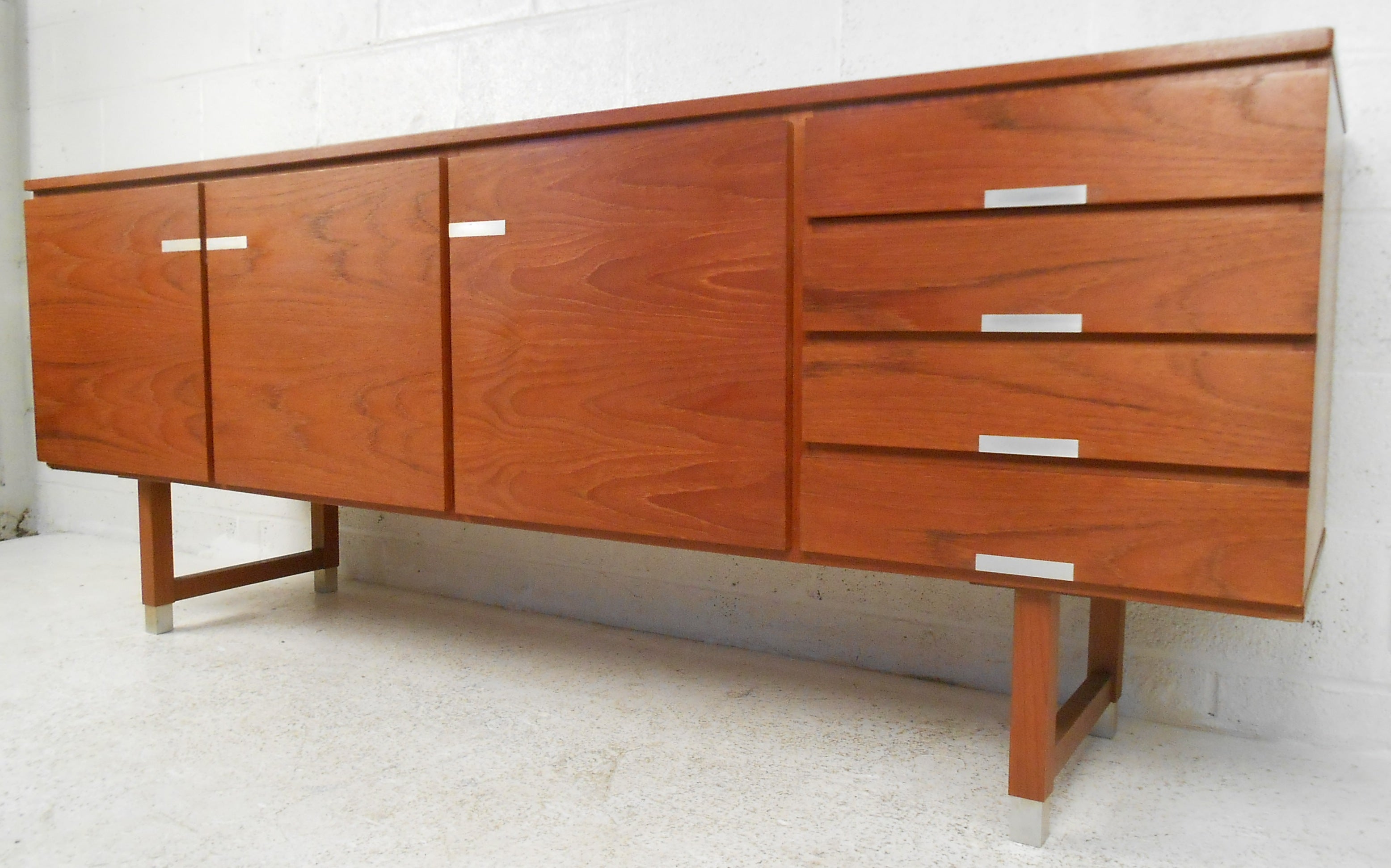 Long teak server by Kai Kristiansen featuring four drawers and three doors with adjustable shelving makes the perfect storage piece for any modern home. Midcentury design is evidenced in the high quality manufacturing, unique metal trim, and