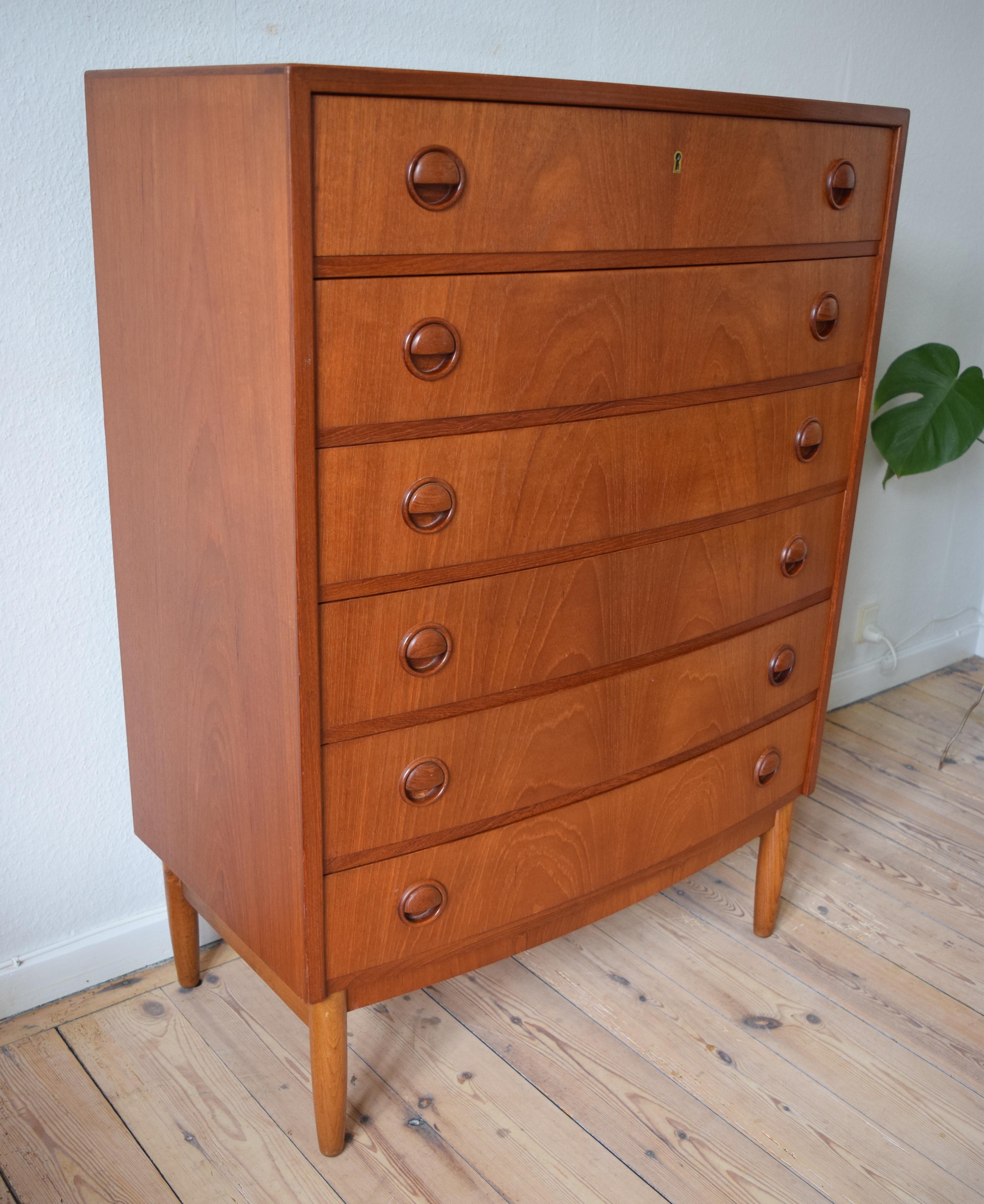 Elegant, large chest of drawers designed by Kai Kristiansen circa 1960. The teak chest sits on top of an oak frame and features a slightly bowed front, round drawer pulls and a lockable top drawer.
 