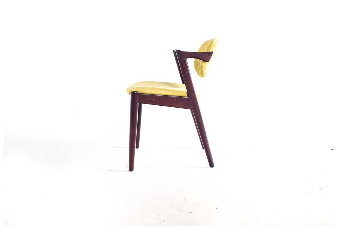 This set of 4 dining chairs, model 42, is a mid-century modern masterpiece designed by renowned Danish designer Kai Kristiansen in 1963. Crafted from rich teak wood, these chairs are celebrated for their impeccable craftsmanship and timeless