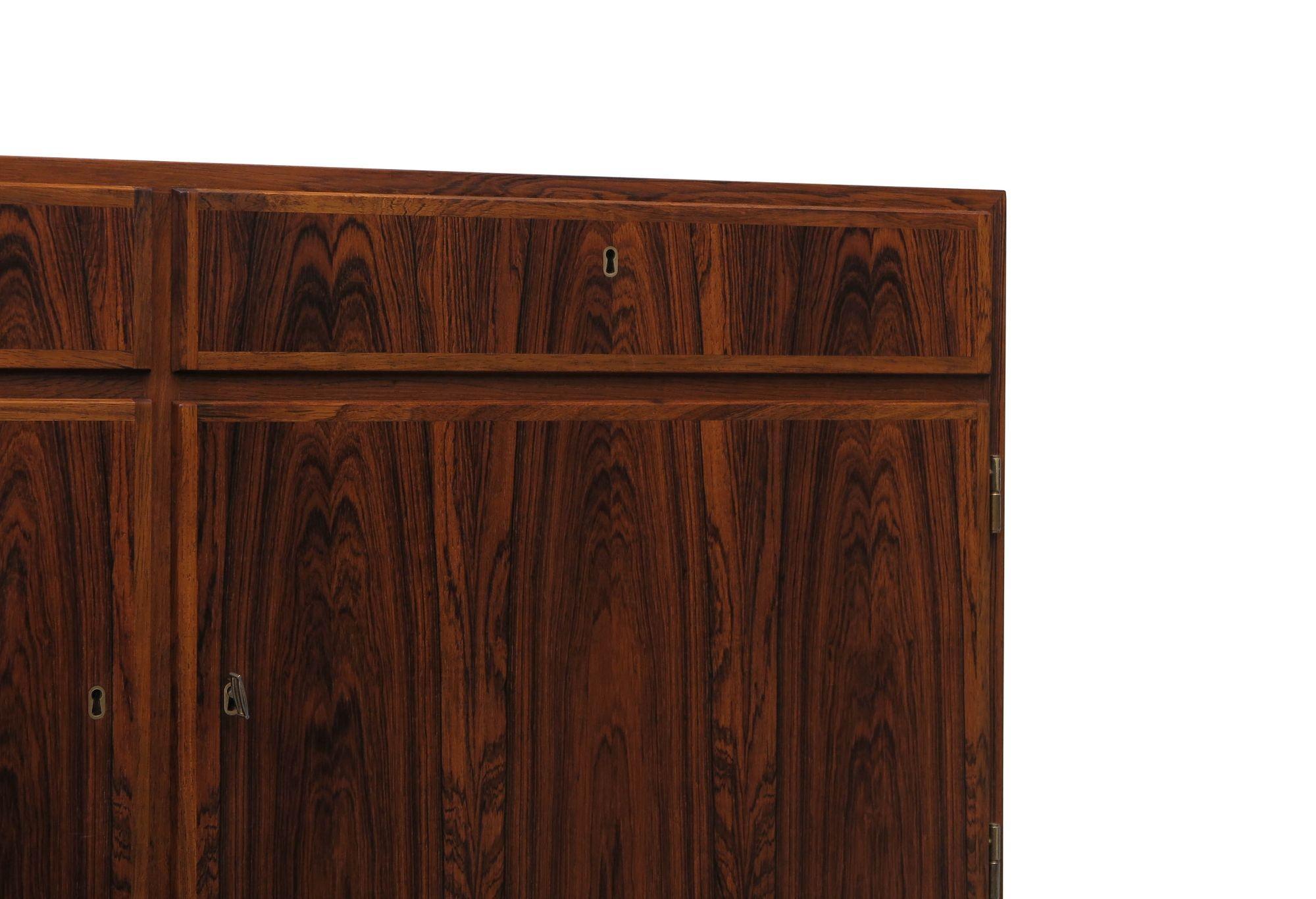 Mid-century Danish rosewood credenza designed by Kai Winding in 1958, Denmark. This finely crafted cabinet showcases book-matched rosewood with mitered edges and locking doors and drawers, with a mahogany interior with adjustable shelves, and