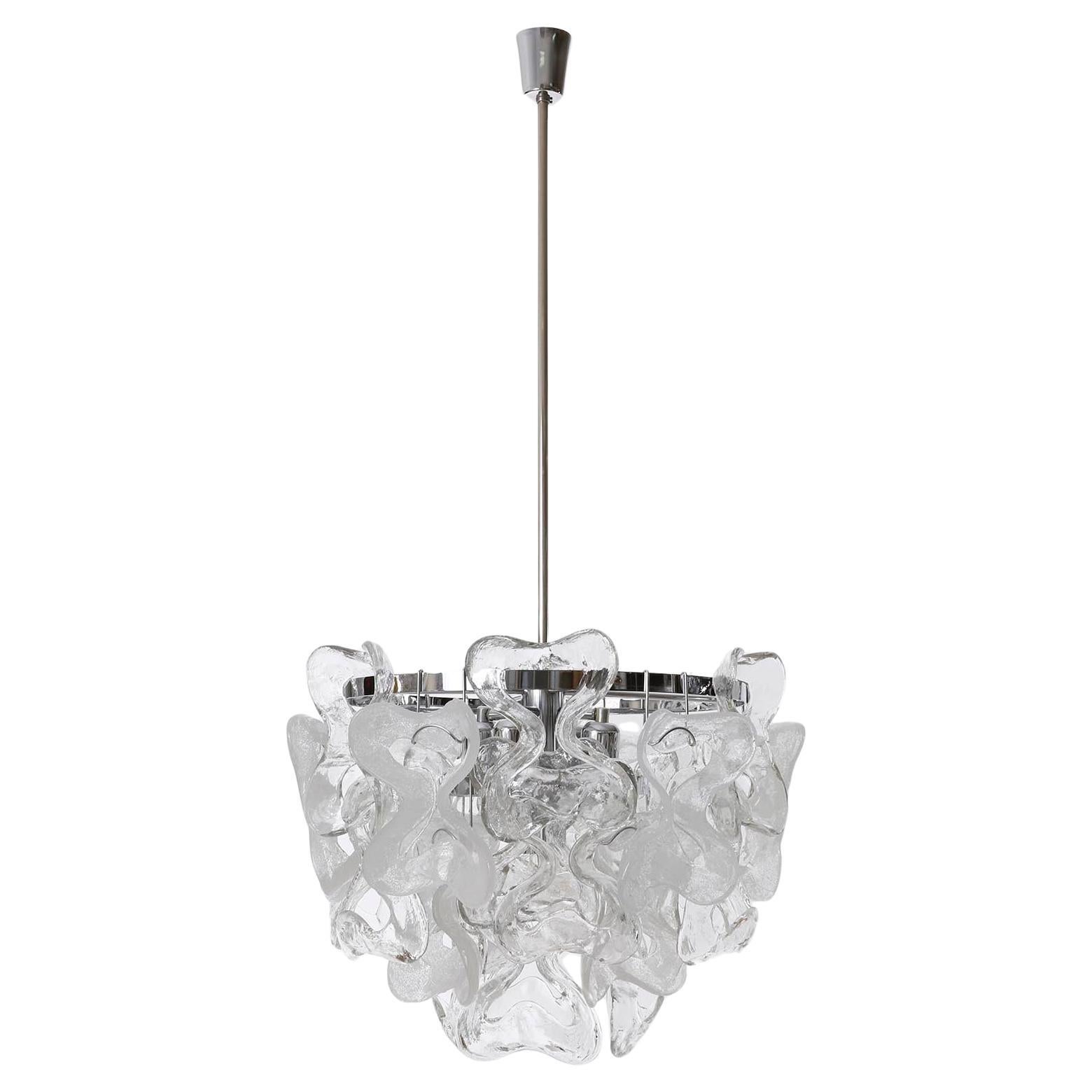 A large and fantastic Mid-Century modern light fixture model 'Catena' by J.T. Kalmar, Austria, manufatured in 1970s-1980s. 
It consists of a polished chrome frame with 30 organic and ribbon-shaped Murano glass pieces. 20 are made of clear crystal