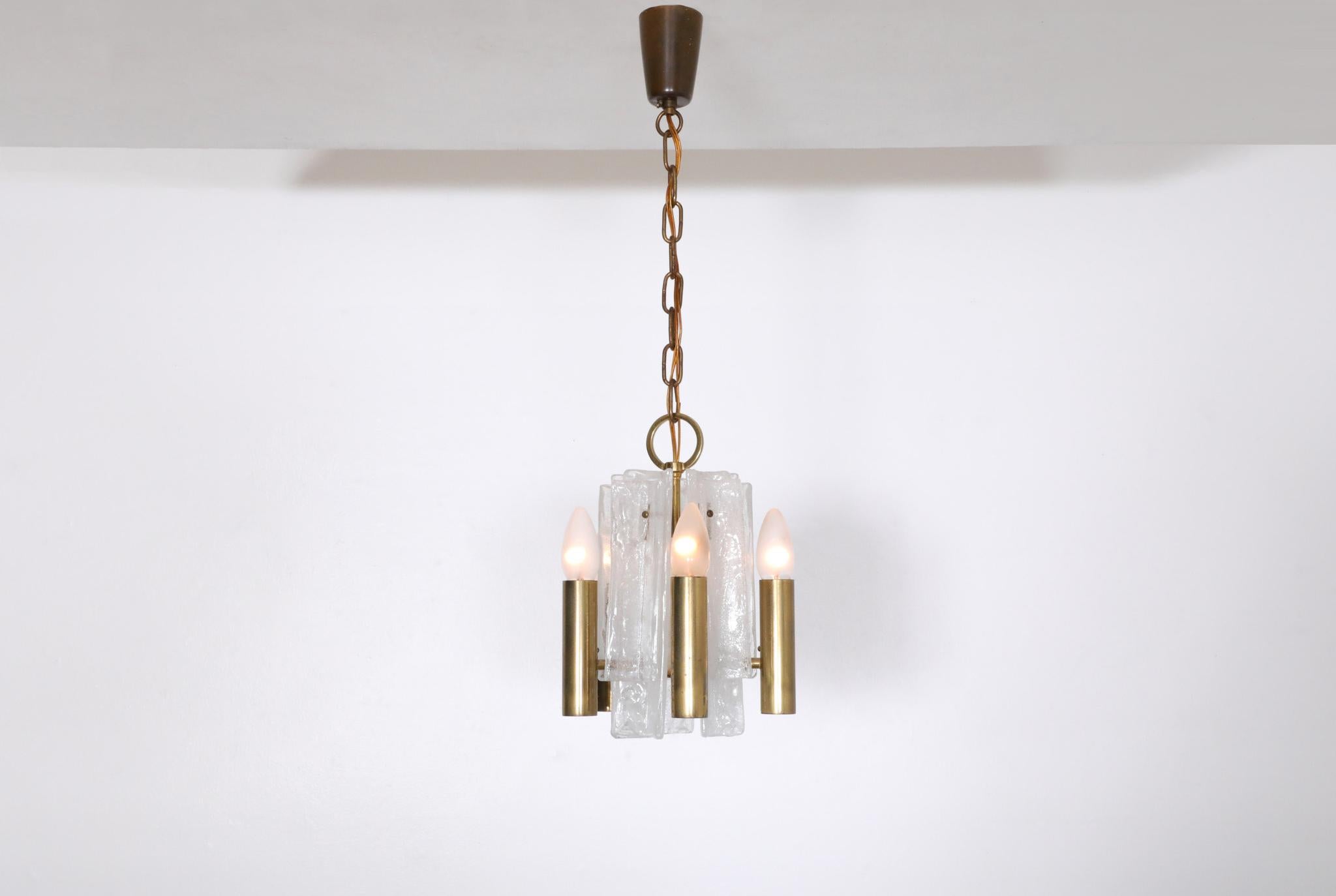 Beautiful, Mid-Century, small, Kalmar manufactured brass chandelier outfitted with 10 layered linear ice glass pieces highlighting the 5 brass tubular sockets. This piece has a brass canopy and is suspended by a brass chain.40watt max per socket.