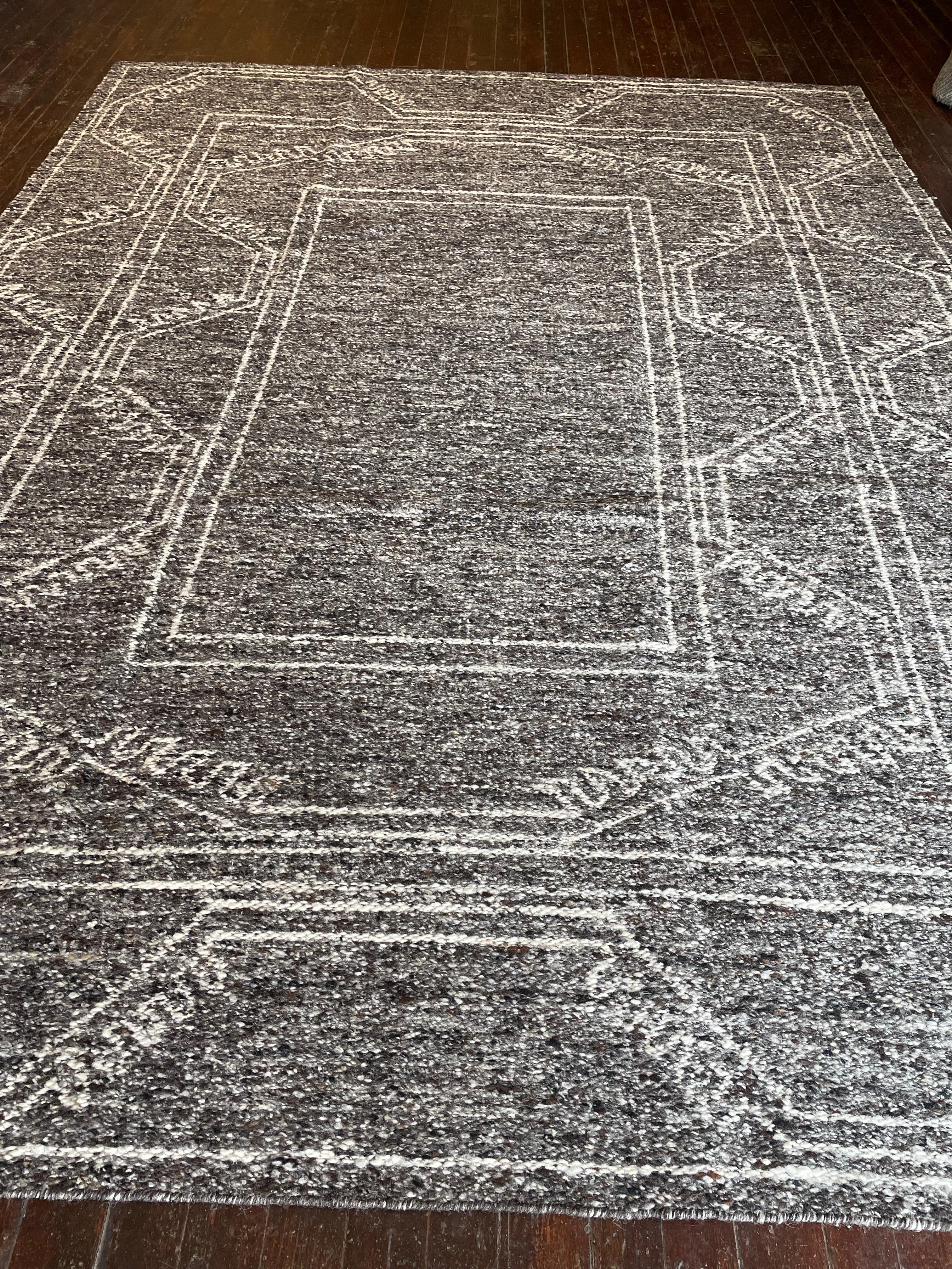 Immergiti nella semplicità senza tempo di questa riproduzione del tappeto Kars a trama piatta, meticolosamente realizzata in India. Originari della regione di Kars, nell'Anatolia orientale, in Turchia, i tappeti di Kars sono famosi per i loro