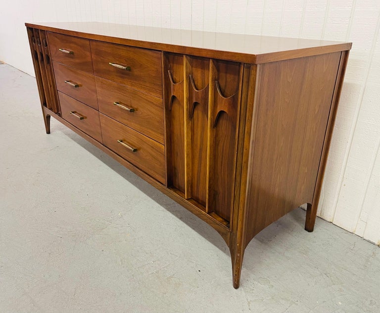 This listing is for a Mid-Century Kent Coffey Perspecta Walnut Triple Dresser. Featuring six center drawers, two doors on each end that open up to three hidden drawers, original hardware, carved rosewood drawer pulls, and a beautiful walnut finish.