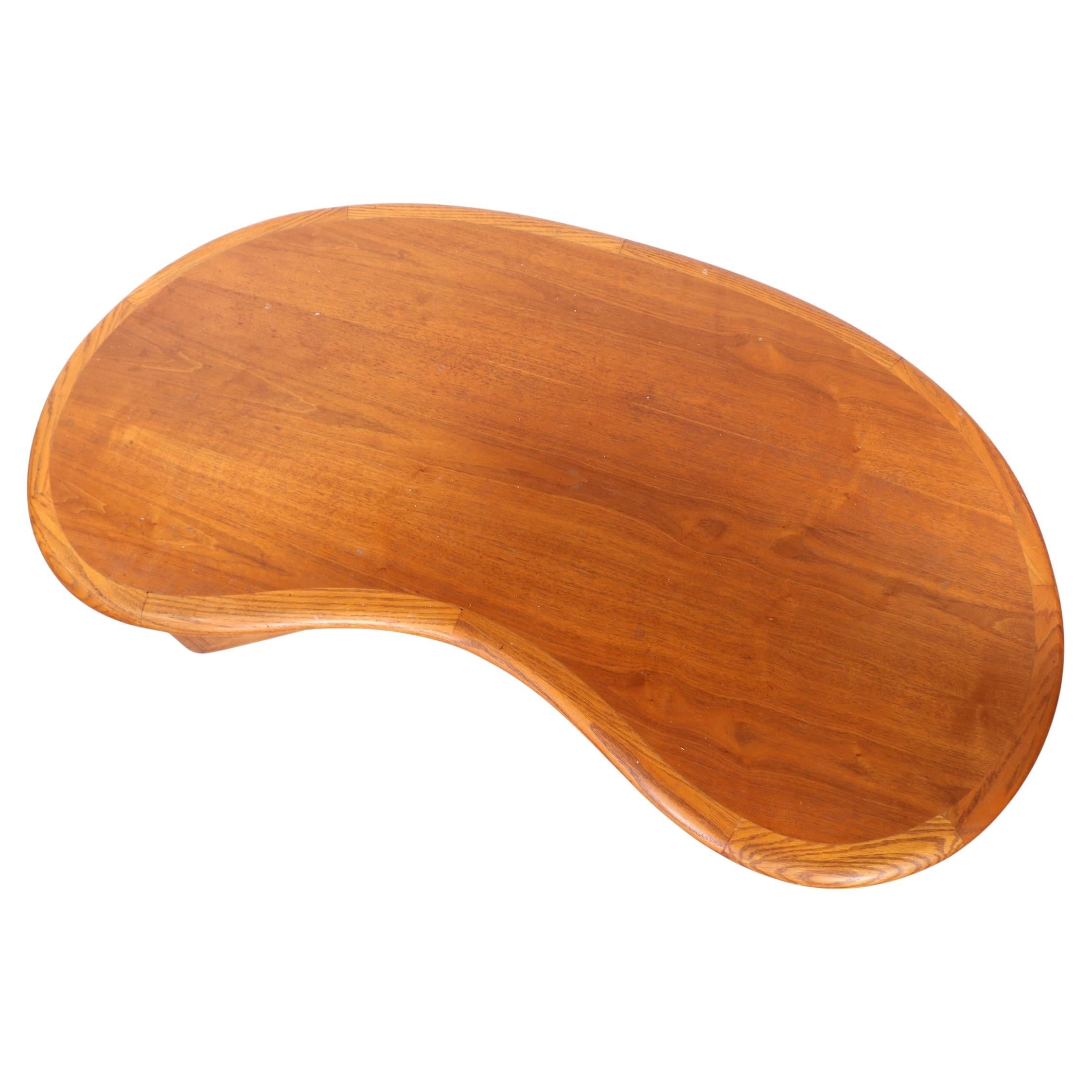 Classic Amoeba, or Kidney Bean form coffee table by the Lane Furniture company, in very good, original, clean and ready to use condition. The table features a thick organic form top, mounted on intersecting stylized legs. 
 This example is fully and