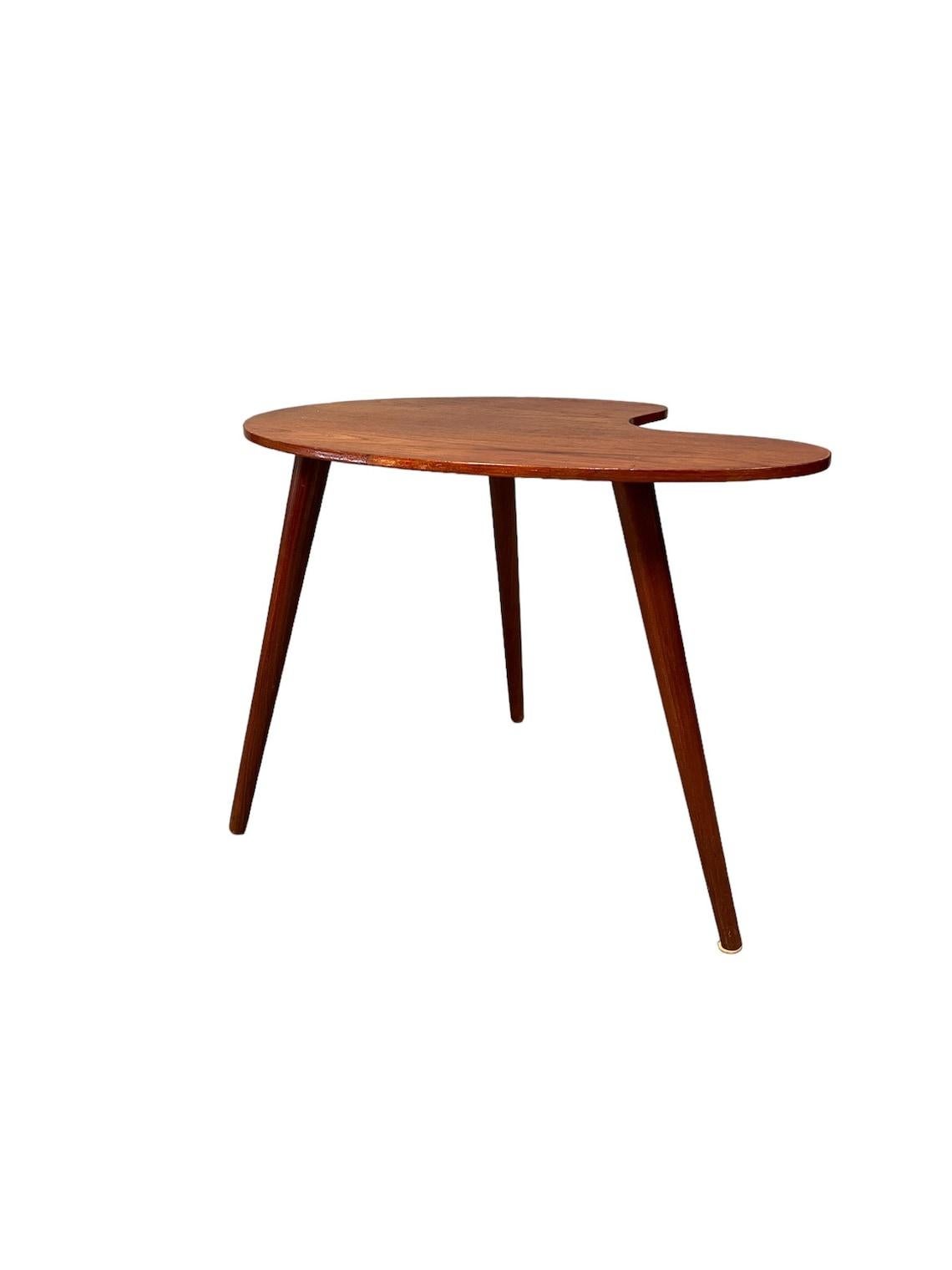This unique Mid- Century Kidney Shaped End Table in Teak is the perfect addition to any modern home. The table's kidney shape makes it a unique and eye-catching piece that is sure to stand out in any room. Measuring 18 inches in height and 25 inches