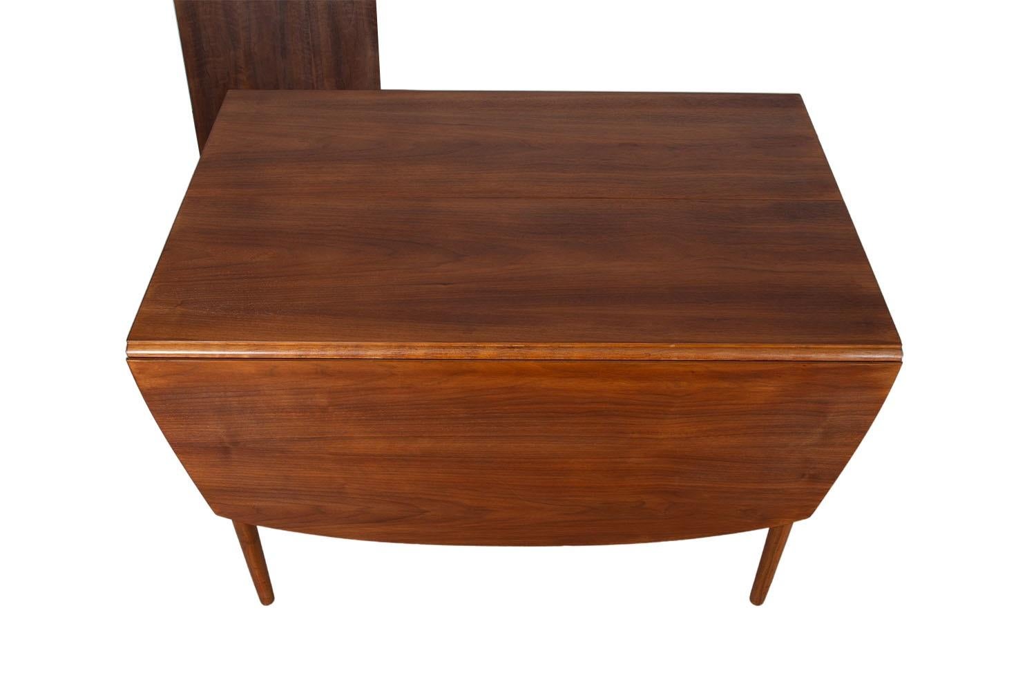 Magnifique table de salle à manger extensible de style moderne du milieu du siècle, conçue par Kipp Stewart pour Drexel/One. Le noyer est richement grainé et les lignes épurées sont caractéristiques du design danois classique. Surélevée sur quatre