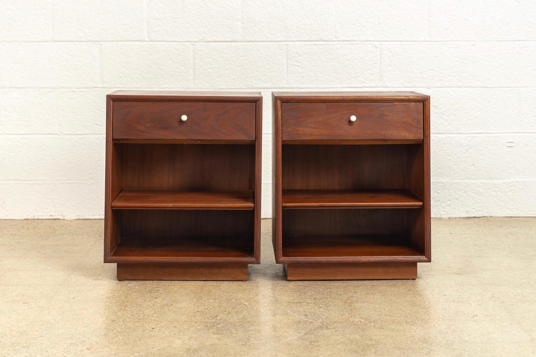 This pair of vintage Mid-Century Modern nightstand tables from 1964 was designed by Kipp Stewart and Stewart McDougall for the iconic Drexel Declaration line. Well constructed from walnut wood, the sleek, streamlined design features one upper drawer