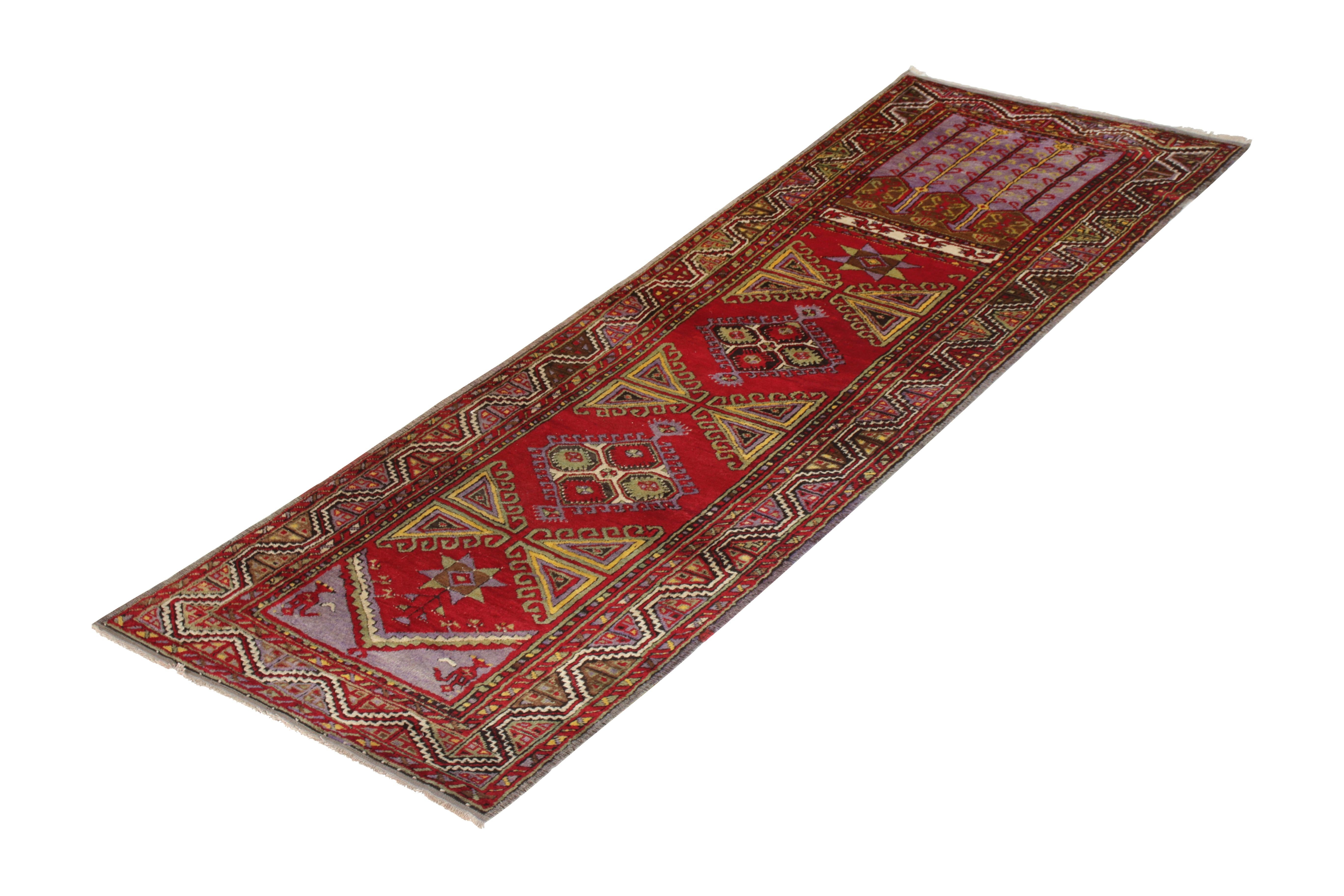 A midcentury vintage Kirsehir Turkish pile rug, this runner comprises wool for its colorful red foundation and complementary purple, pink, green and yellow details. This vintage Turkish runner originated circa 1950-1960 with a vibrant appearance